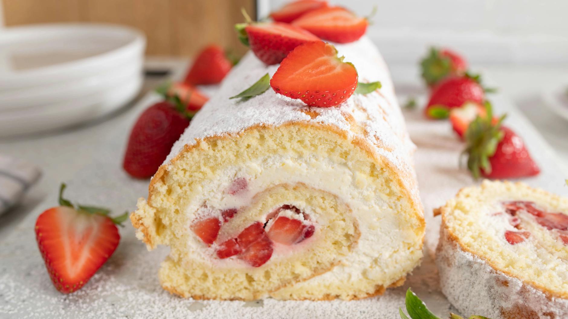 Vor dem Servieren die Erdbeer-Sahne-Rolle mit Puderzucker bestäuben und mit den Früchten garnieren.