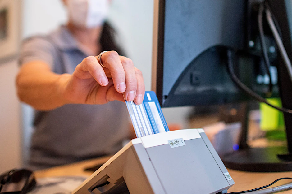 Eine Person schiebt eine Versichertenkarte einer Krankenkasse in ein Lesegerät. Elektronische Rezepte und digitale Patientenakten wurden nach jahrelangen Verzögerungen eingeführt.