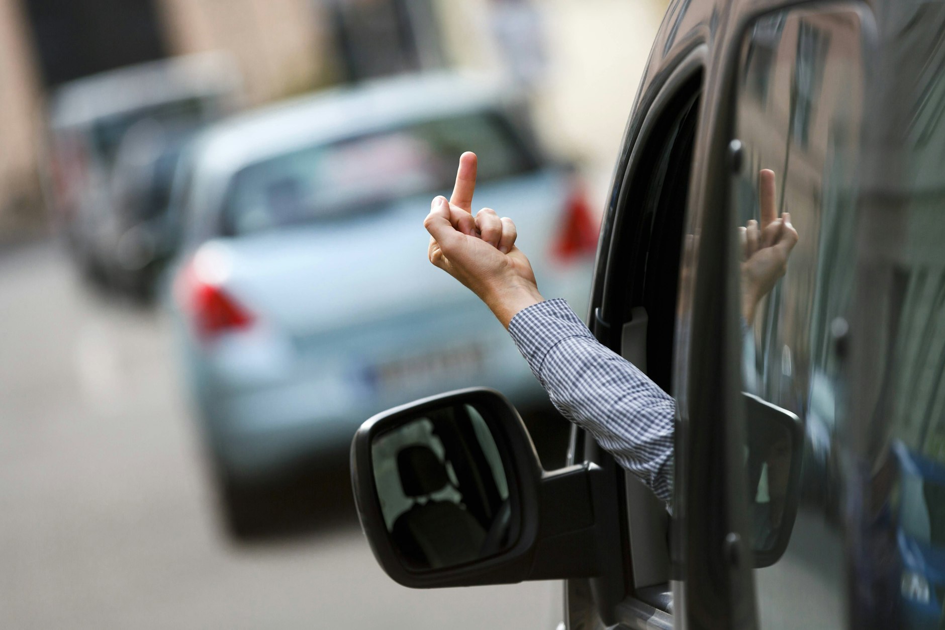 Ein Autofahrer zeigt einem anderen Verkehrsteilnehmer seinen Mittelfinger. Nicht selten wird auch verbal gepöbelt.