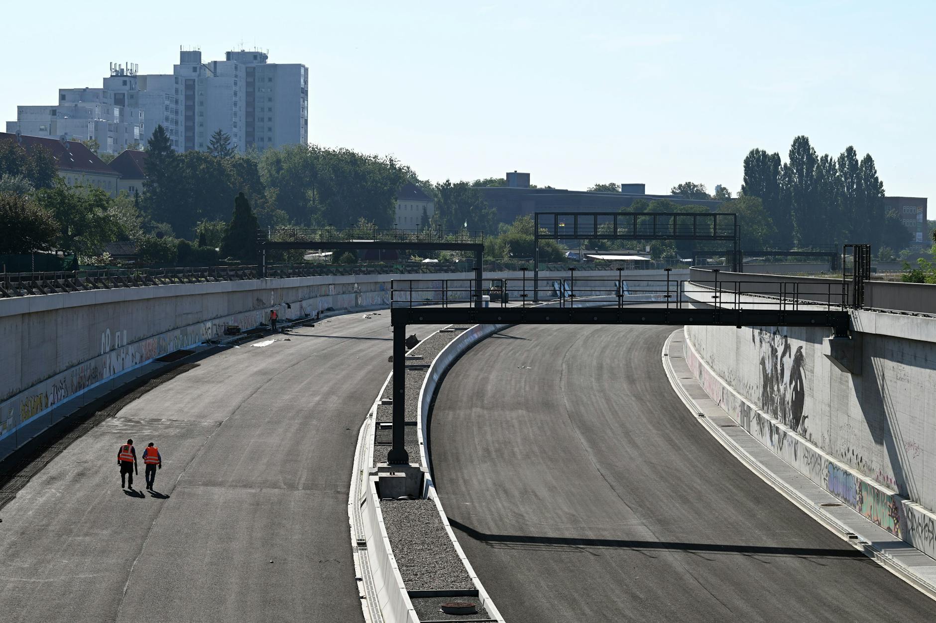 Zwei Arbeiter gehen auf der noch nicht markierten Fahrbahn der Erweiterung der Stadtautobahn A100 zwischen Autobahndreieck Neukölln und Anschlussstelle Treptower Park.
