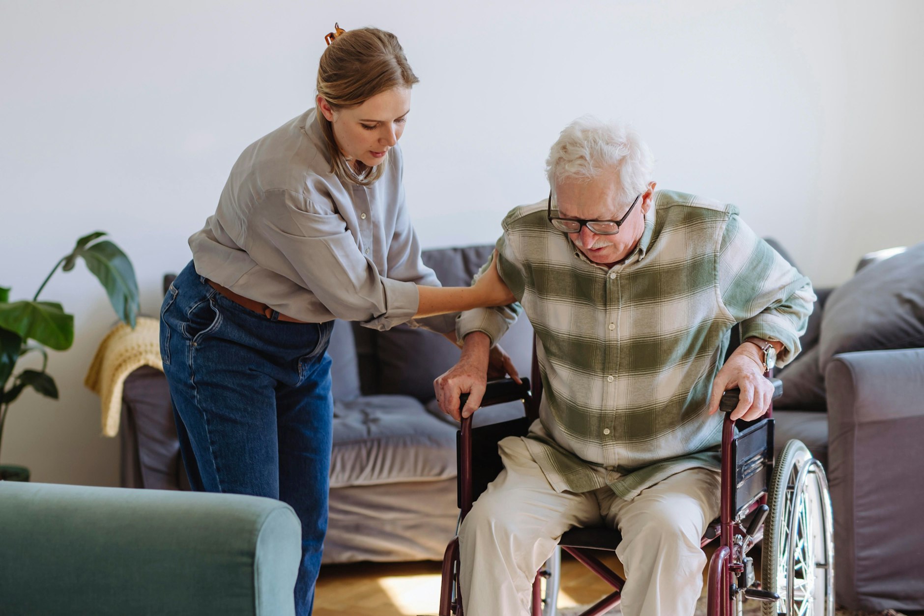 Eine Angehörige hilft einem Mann aus dem Rollstuhl.
