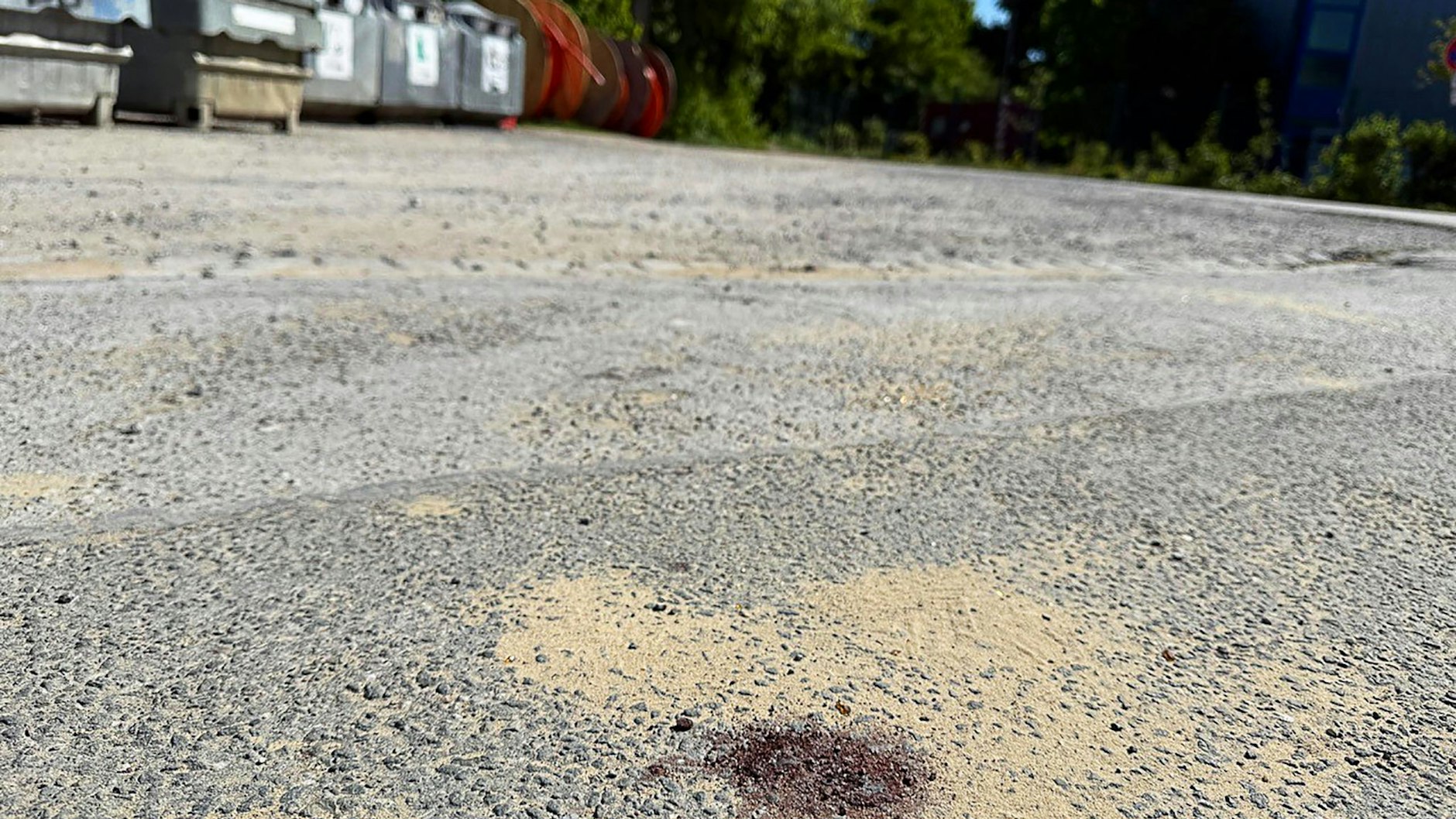 Ein Blutfleck ist auf dem Asphalt am Tatort in Menden im Sauerland zu sehen.