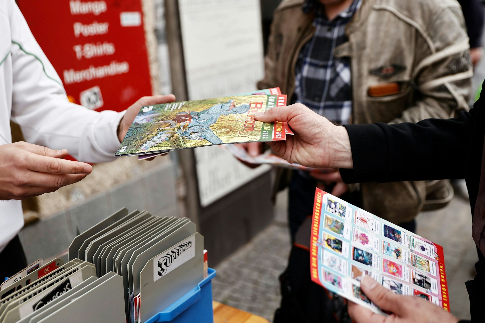 Ein Mitarbeiter sucht für Interessenten vor einer Comic-Buchhandlung Comic-Hefte heraus.
