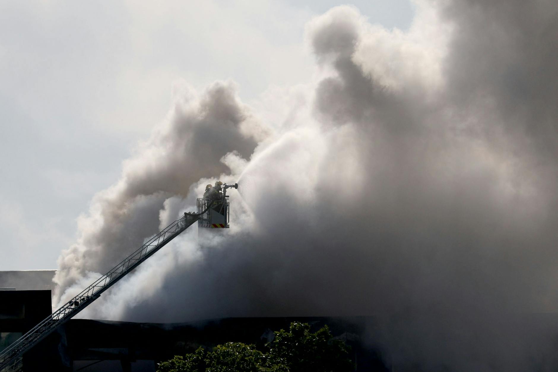 Feuerwehrleute auf einer Hebebühne am 10. Mai 2025 in der Küstenstadt Vilanova i la Geltru, südlich von Barcelona. In einem Gebäude, in dem Reinigungsmittel für Schwimmbecken gelagert werden, war ein Feuer ausgebrochen..