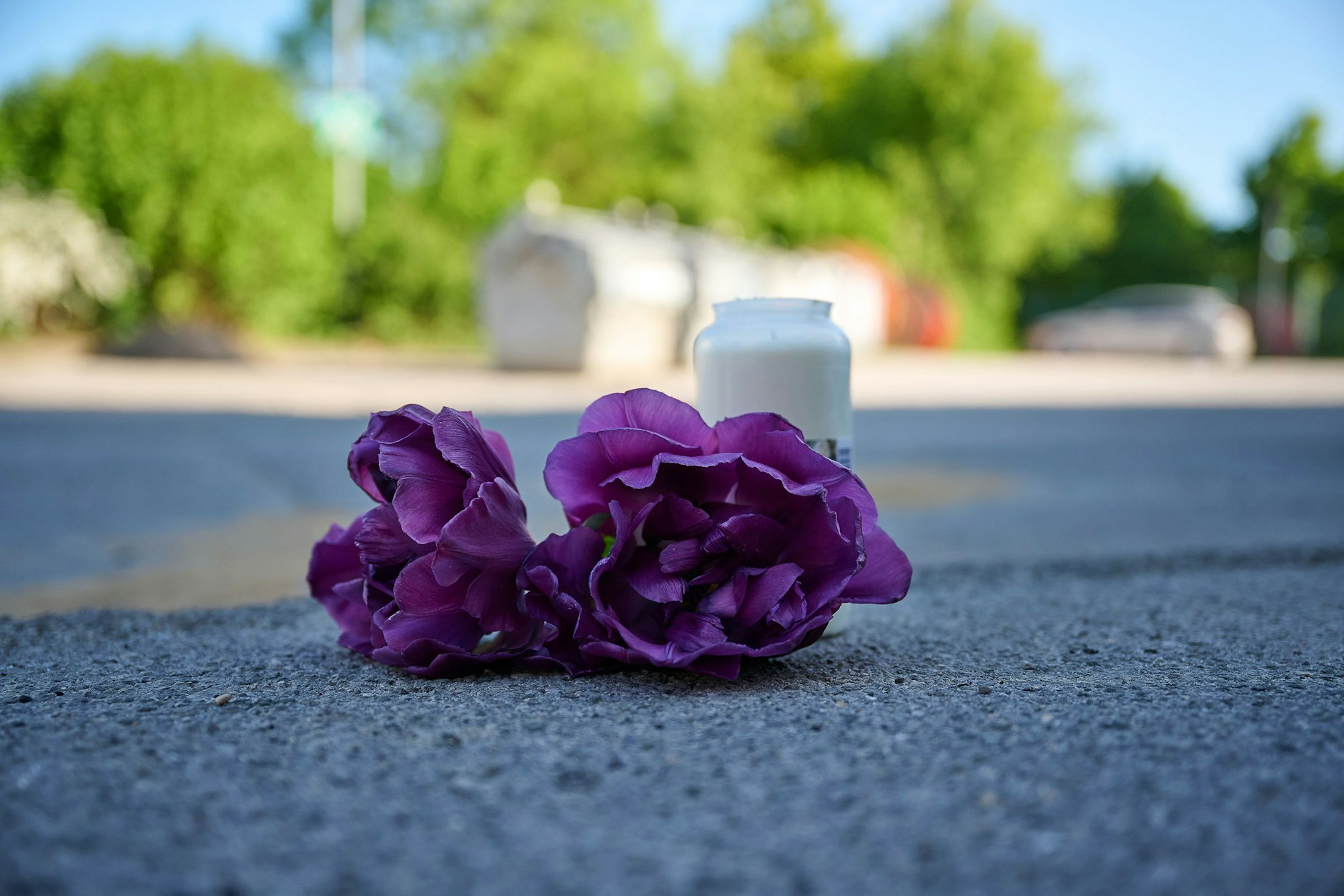 Blumen und eine Kerze liegen auf einem Schotterplatz vor dem Eingang zu einem Spielplatz. In Menden im Sauerland soll in der Nacht ein 17-Jähriger einen 14-Jährigen erstochen haben.