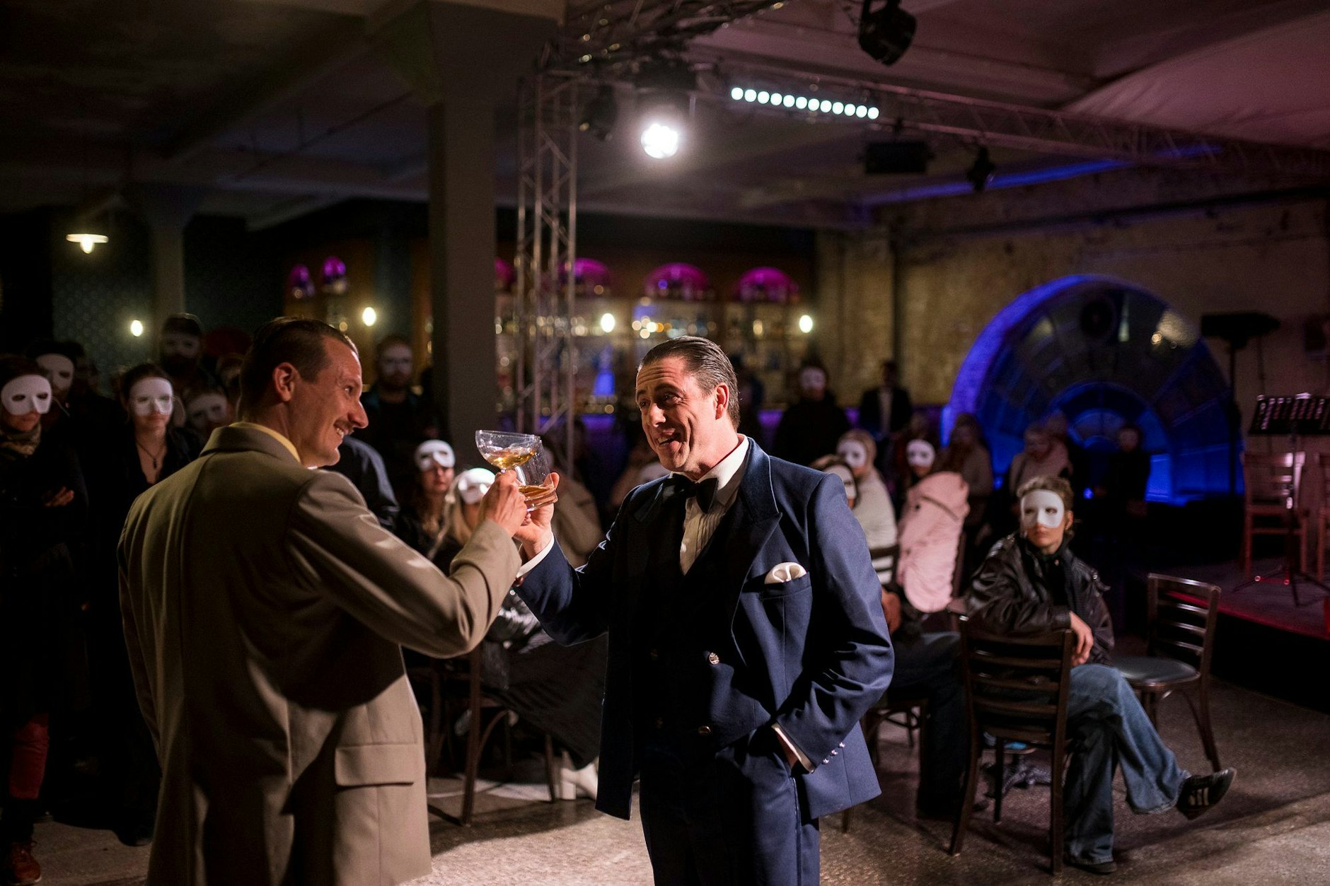 Nick (Jonte Volkmann, l.) und Jay (Philip Heimke) lernen sich im Fitzgerald’s kennen. Szene aus „Gatsby!“&nbsp;Die mit den weißen Masken sind Zuschauer.