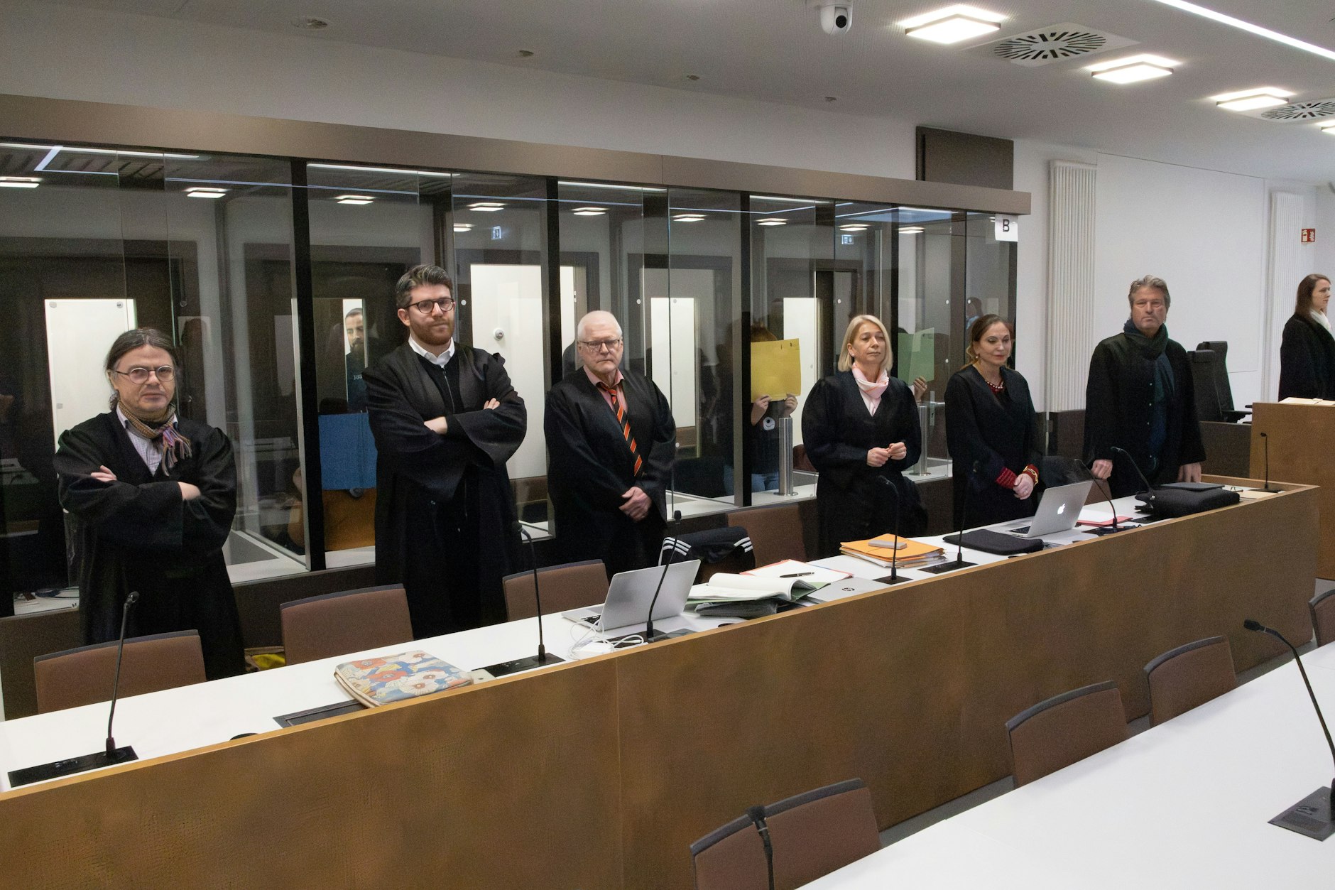 Im Prozess stehen die vier Angeklagten Frauen hinter ihren Anwälten.