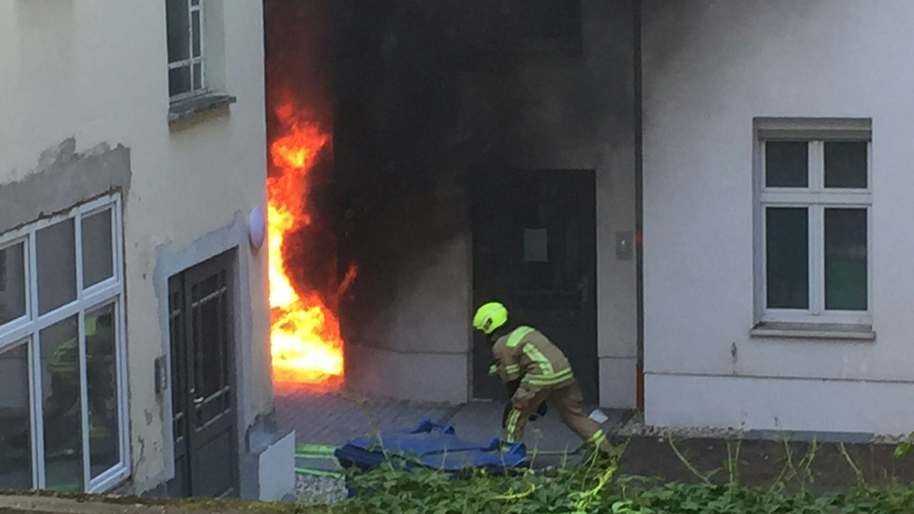 Ein Feuerwehrmann bringt seinen Wasserschlauch in Stellung. Das Feuer ist bedrohlich groß.