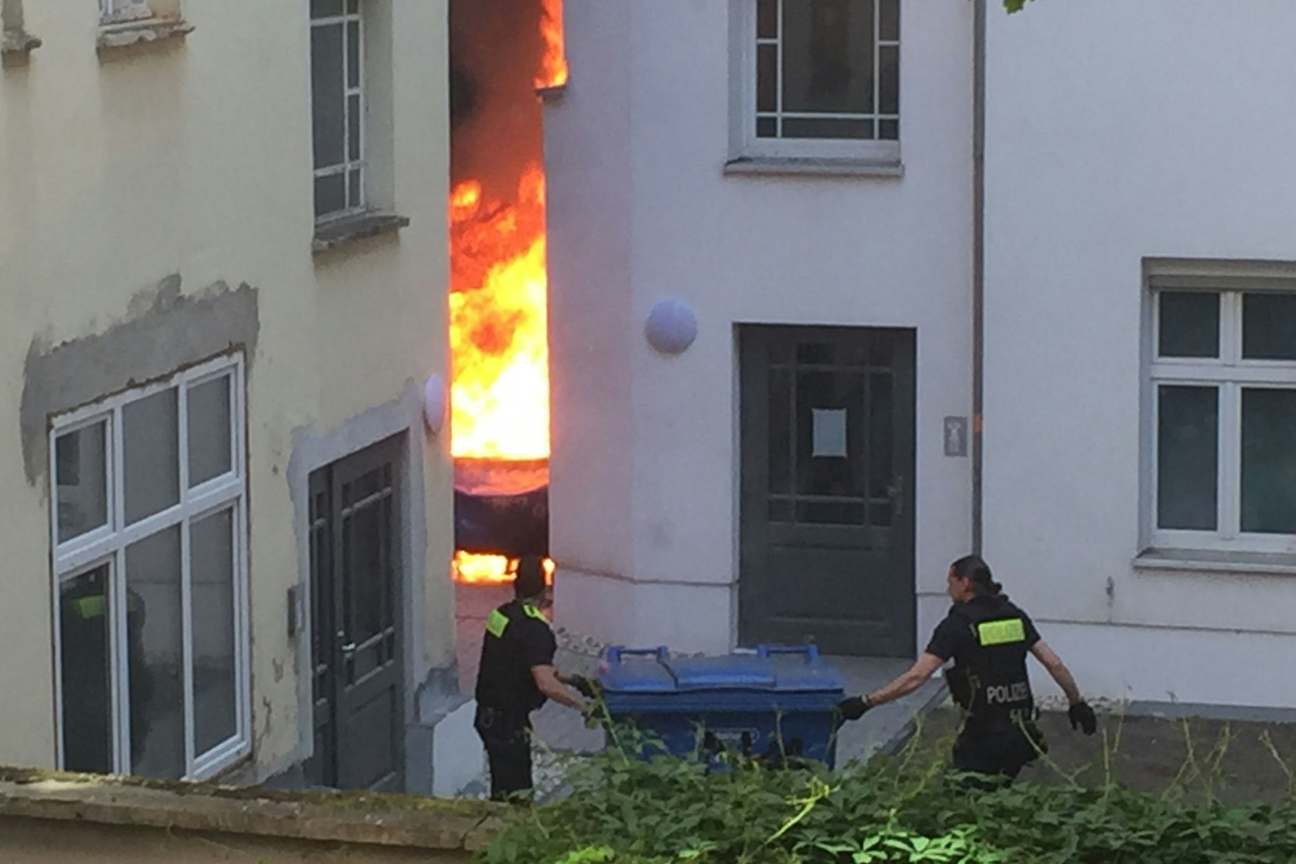 Zwei Polizisten versuchen, eine Tonne aus der Flammenzone zu ziehen.