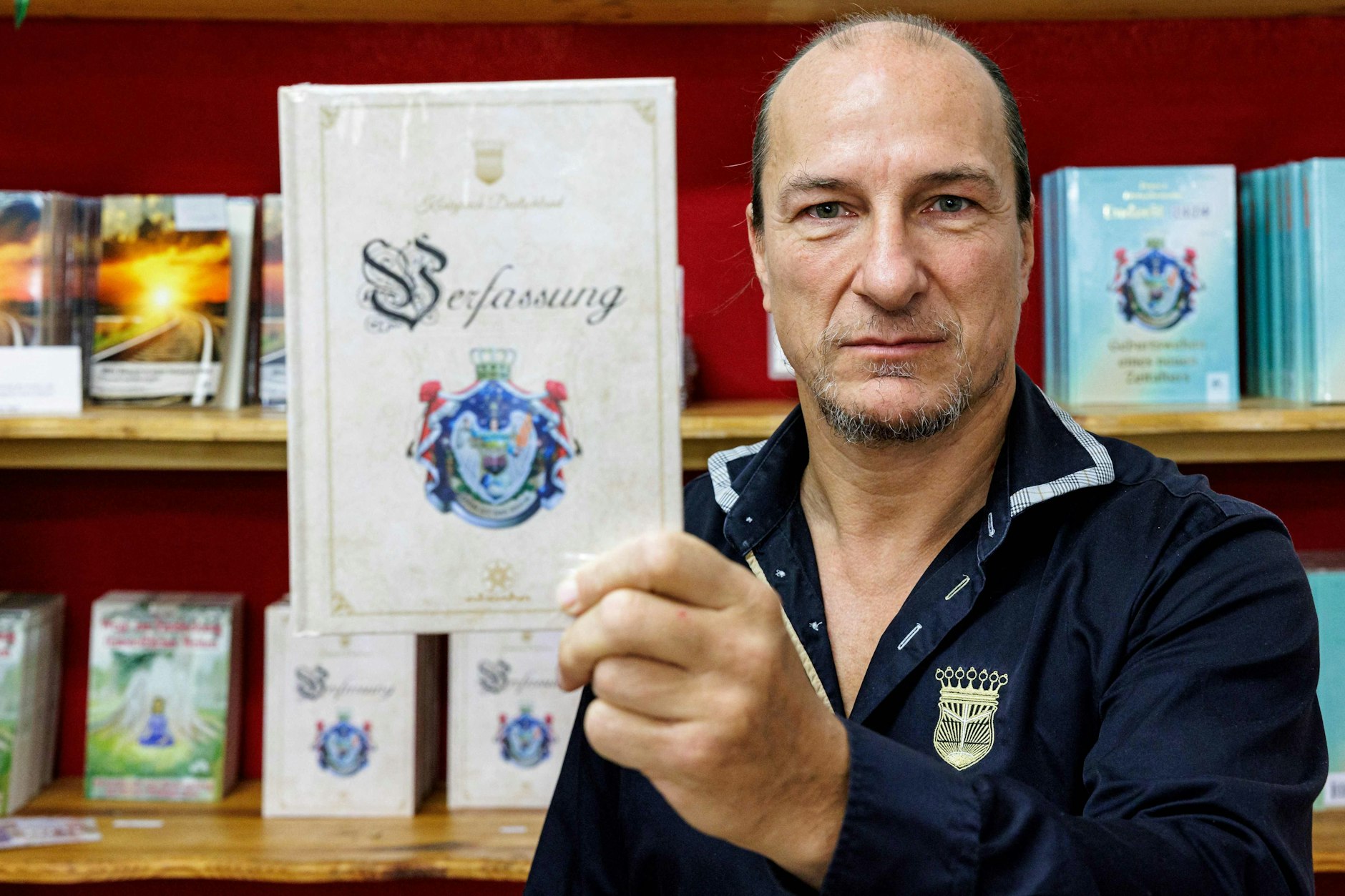 Peter Fitzek, selbsterklärter König von Deutschland, hält die Verfassung seines Fantasiestaates in die Kamera.