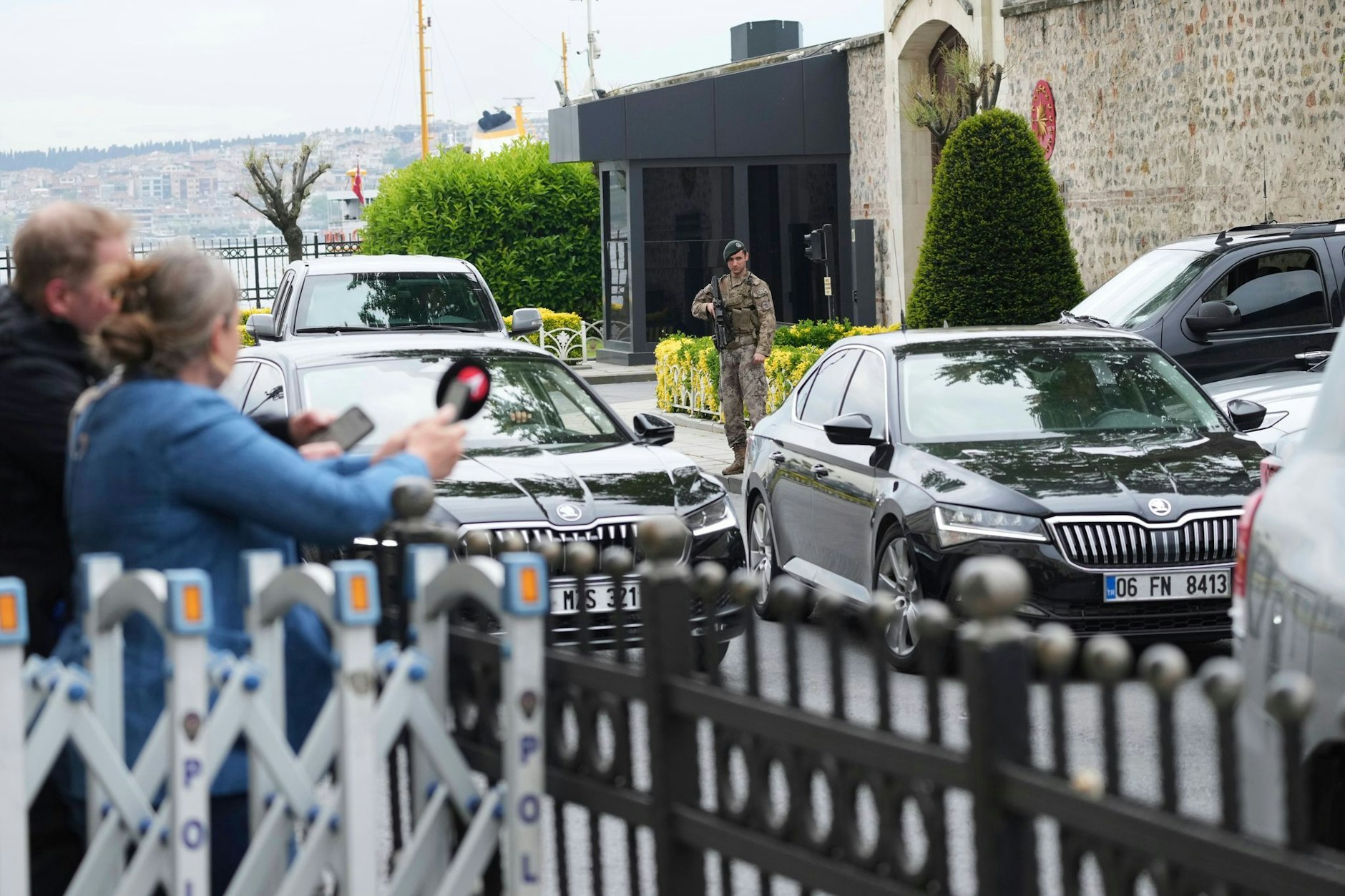 Journalisten hinter einer Absperrung, während Fahrzeuge vor den Gesprächen zwischen Russland und der Ukraine eintreffen.