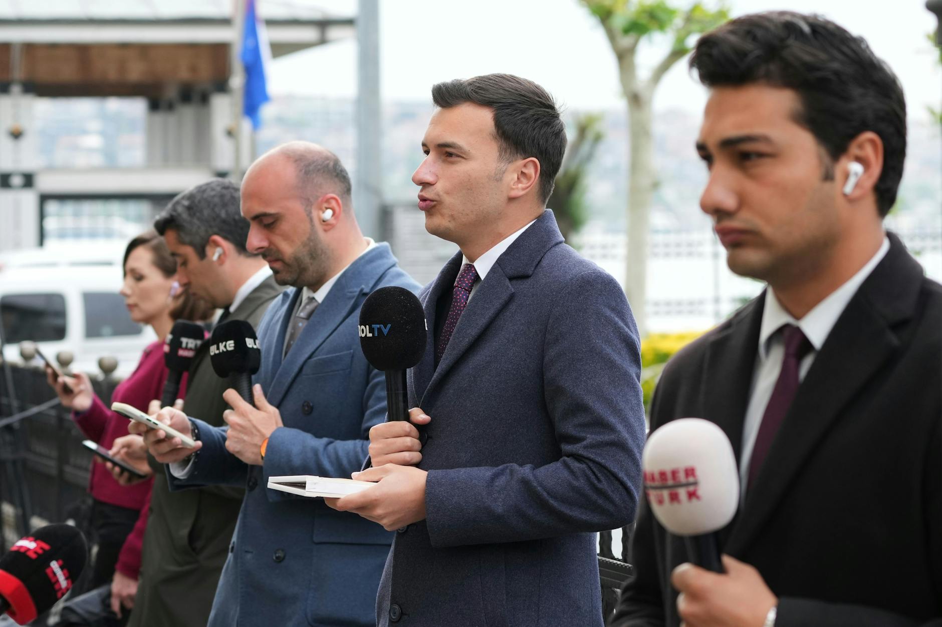 Journalisten nehmen vor möglichen Gesprächen zwischen Russland und der Ukraine hinter einer Absperrung Platz.