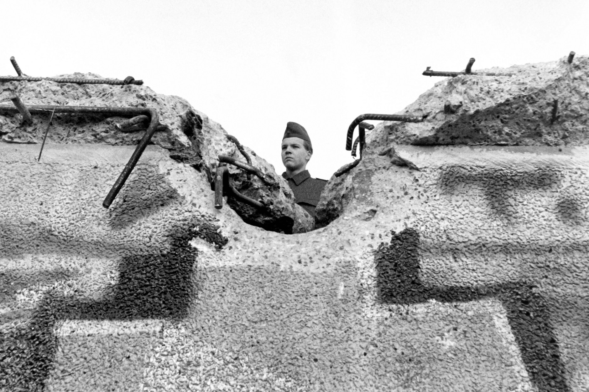 Ein Soldat der DDR-Grenztruppen schaut über eine zerstörte Mauer. Ein Foto vom 12.11.1989.