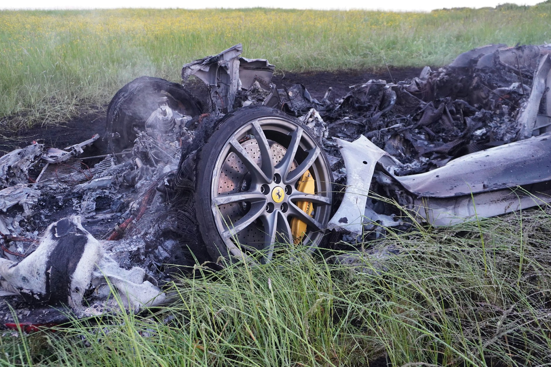 Die Überreste des abgebrannten Ferrari liegen auf einer Wiese neben der Autobahn bei Leutkirch. Beide Insassen überlebten schwer verletzt.