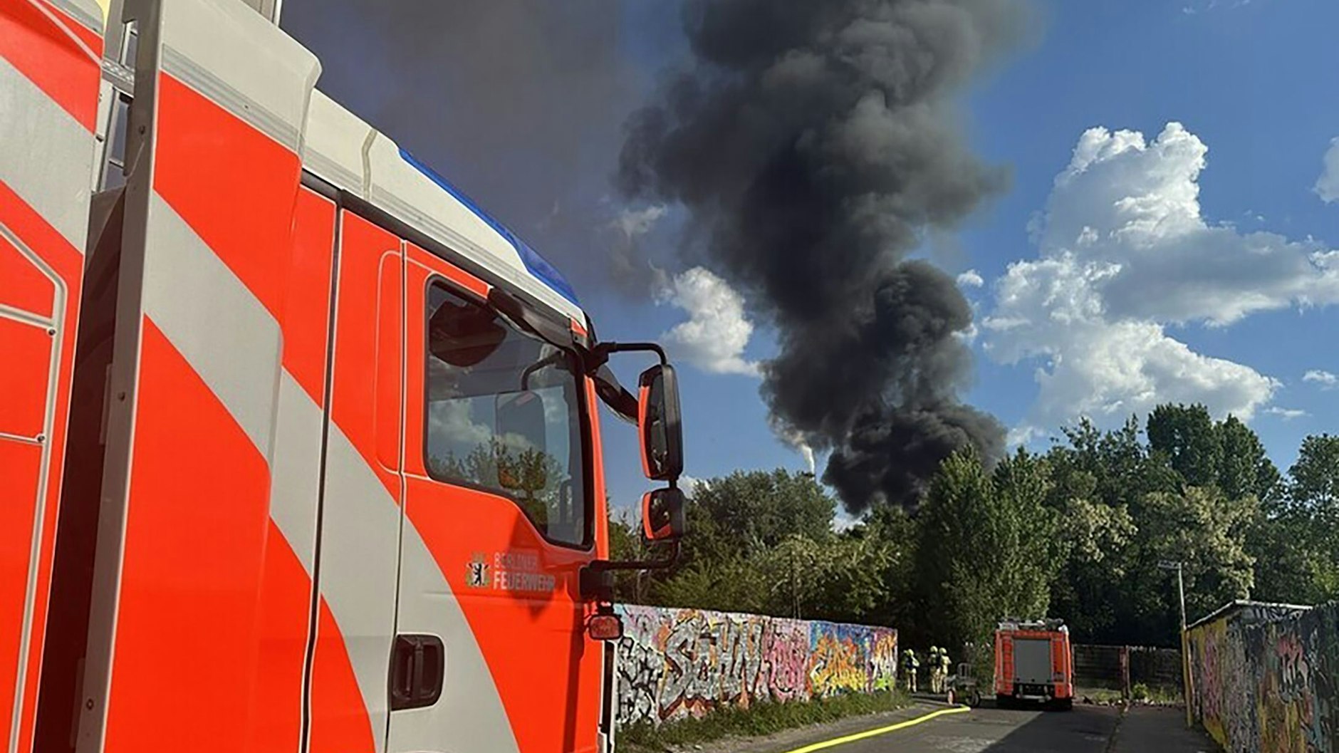 Ein Löschzug der Feuerwehr trifft am Einsatzort ein, nachdem in einer Kleingarten-Kolonie ein Feuer ausgebrochen ist. Mehrere Gartenlauben stehen in Flammen.