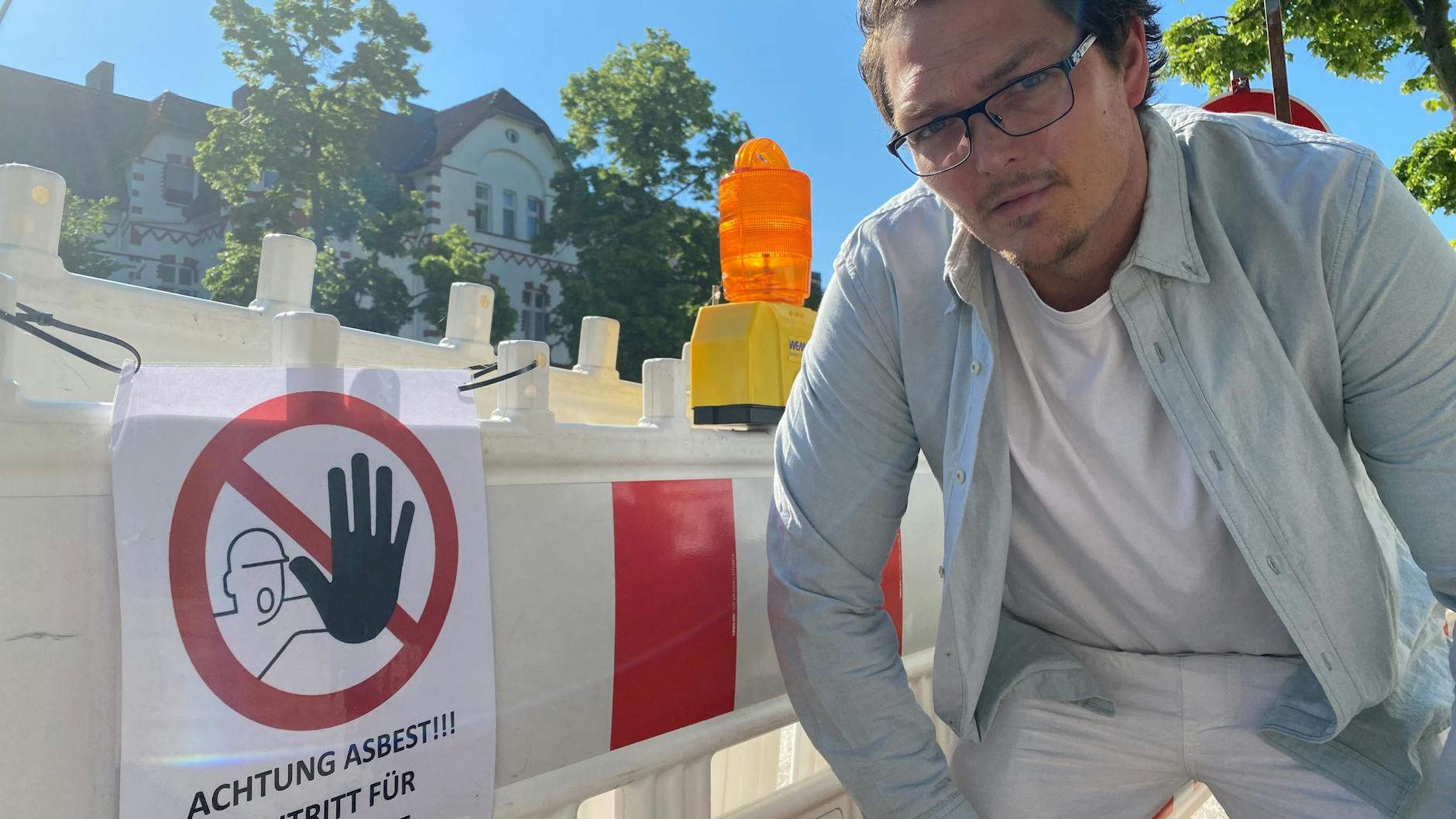 Dennis Böttcher zeigt auf das Asbest-Warnschild, das erst vor wenigen Tagen an dem Baumzaun an der Filandastraße angebracht wurde und für Verwunderung bei den Anwohnern sorgte.