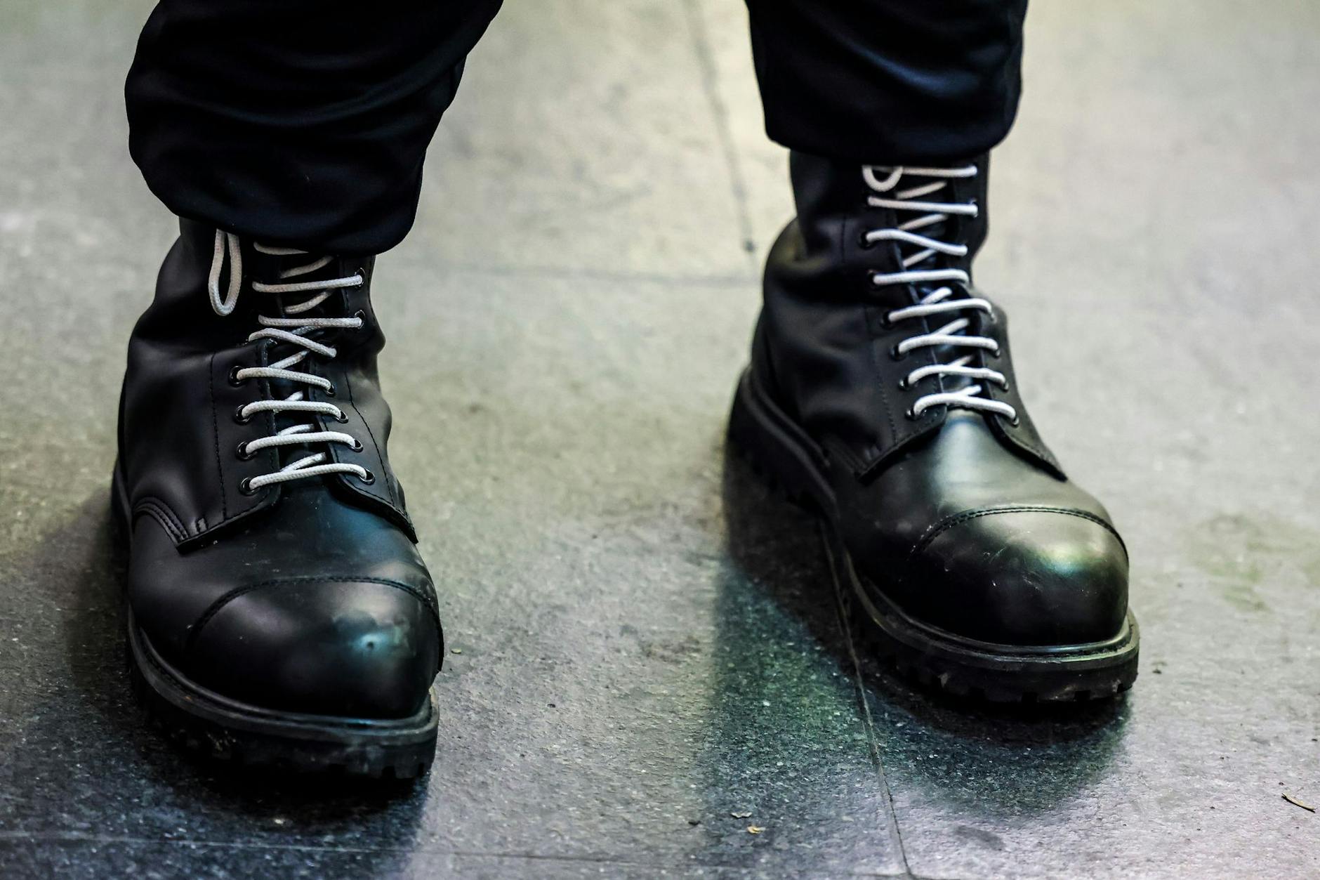 Ein Teilnehmer einer rechtsextremen Kundgebung trägt schwarze Springerstiefel mit weißen Schnürriemen.