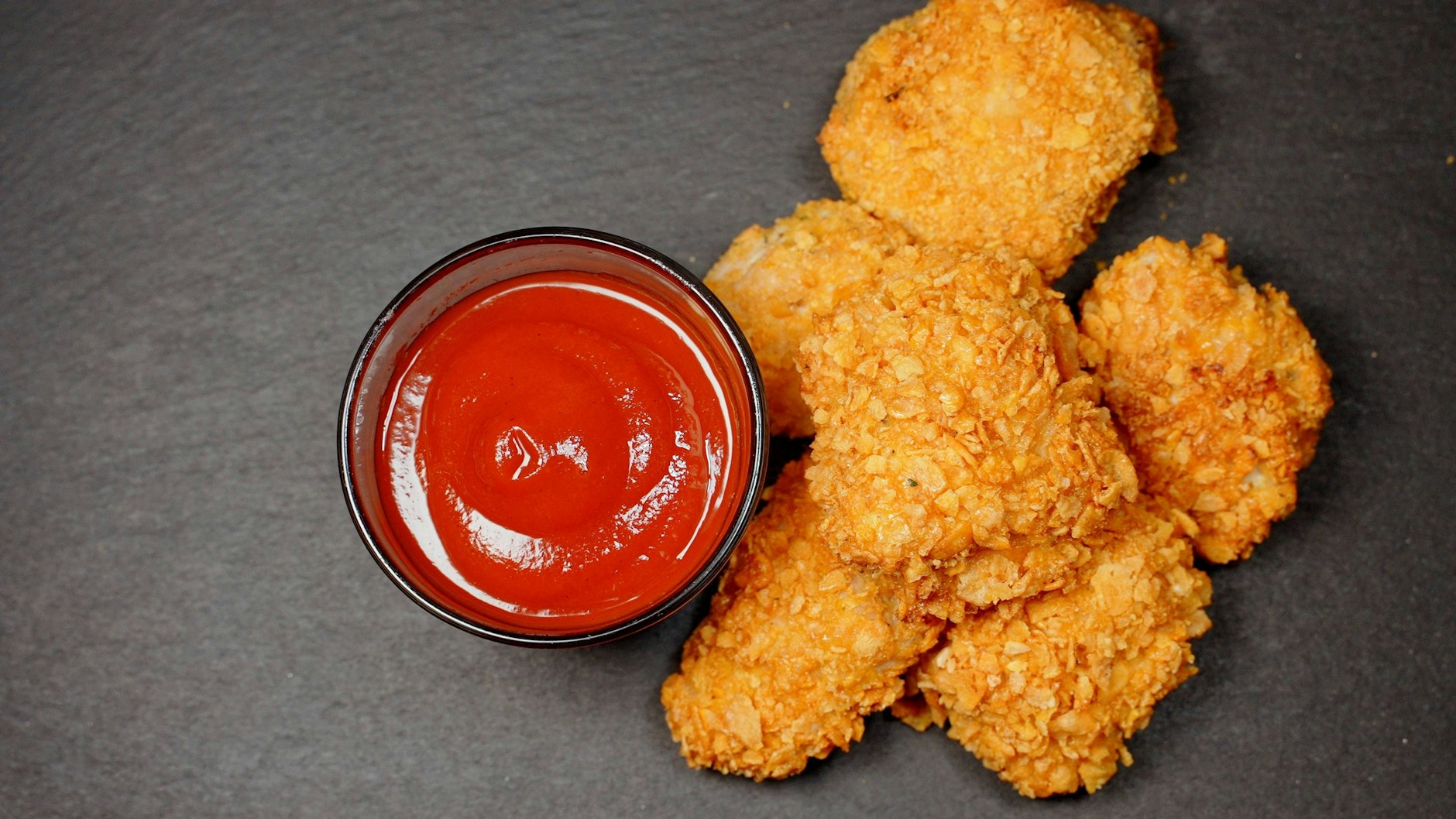 Die Hähnchenstücke werden mit Panko-Mehl besonders kross und schmecken köstlich mit Ketchup.