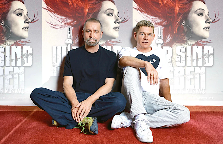 Ulf Leo Sommer (l.) und Peter Plate vor dem Poster ihres nächsten Musicals: „Wir sind am Leben“