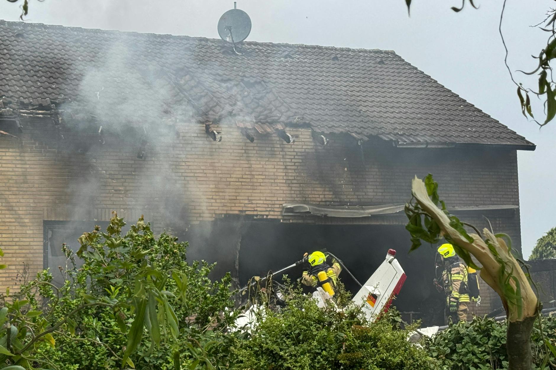 Der Absturz des Flugzeuges in ein Wohnhaus löste einen Brand aus, Feuerwehr und Rettungskräfte sind mit einem Großaufgebot vor Ort.