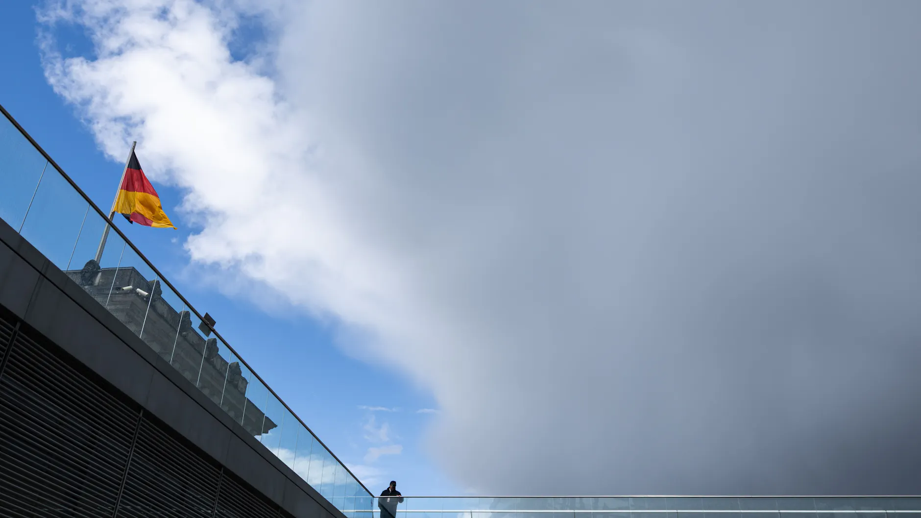 Wolken ziehen über eine Deutschland-Flagge auf dem Reichstagsgebäude.