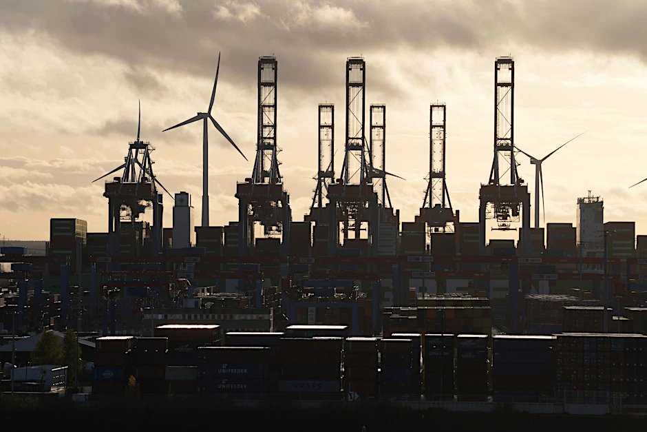 Die Sonne scheint durch dicke Wolken über dem Container Terminal im Hamburger Hafen.