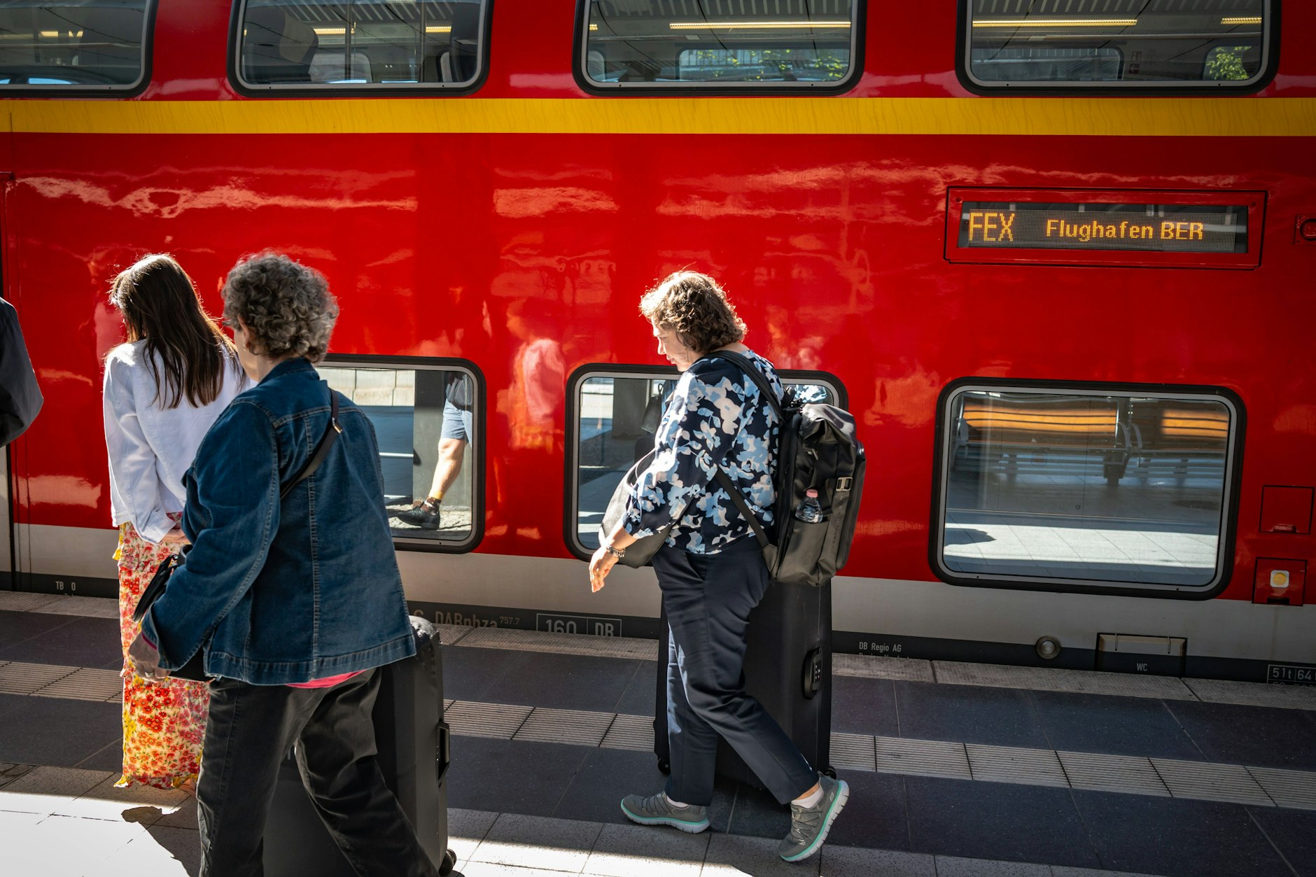 Reisende vor einem Zug der Flughafen-Bahnlinie FEX: Hier gibt es zahlreiche Ausfälle und Änderungen.