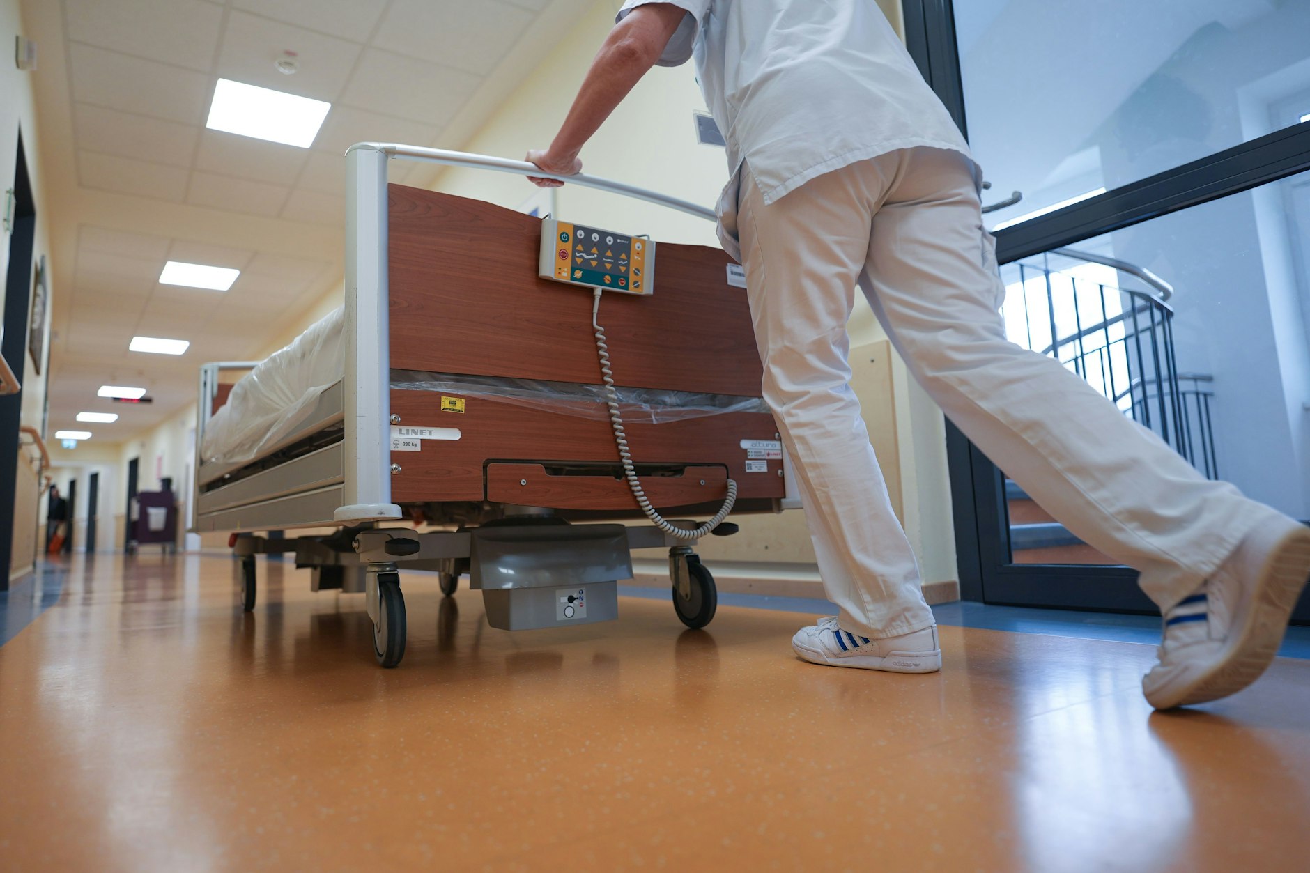Eine Krankenschwester schiebt ein Bett über den Flur einer Krankenstation.