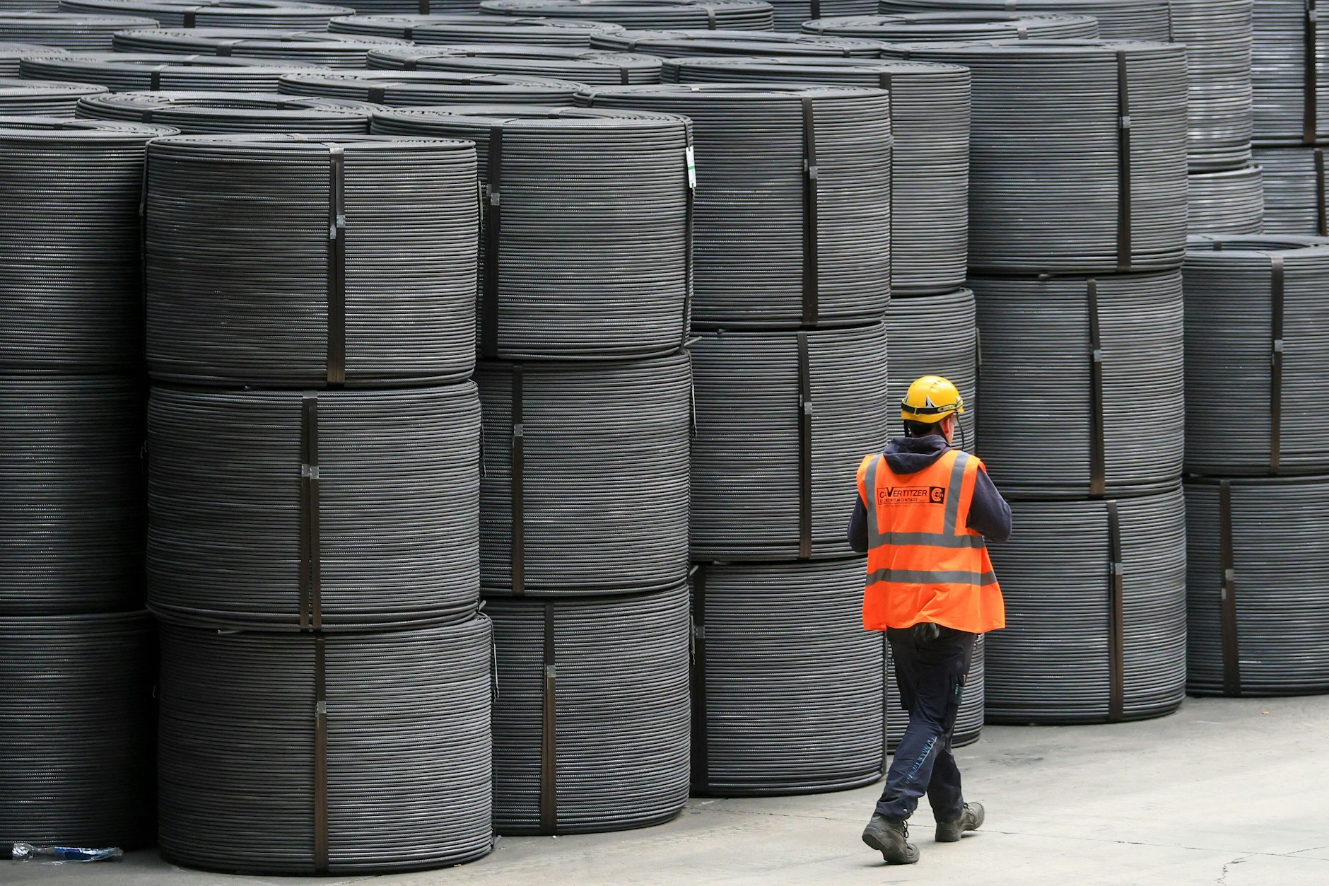 Ein Mitarbeiter geht an Drahtrollen in den Elbe-Stahlwerken Feralpi in Riesa vorbei.