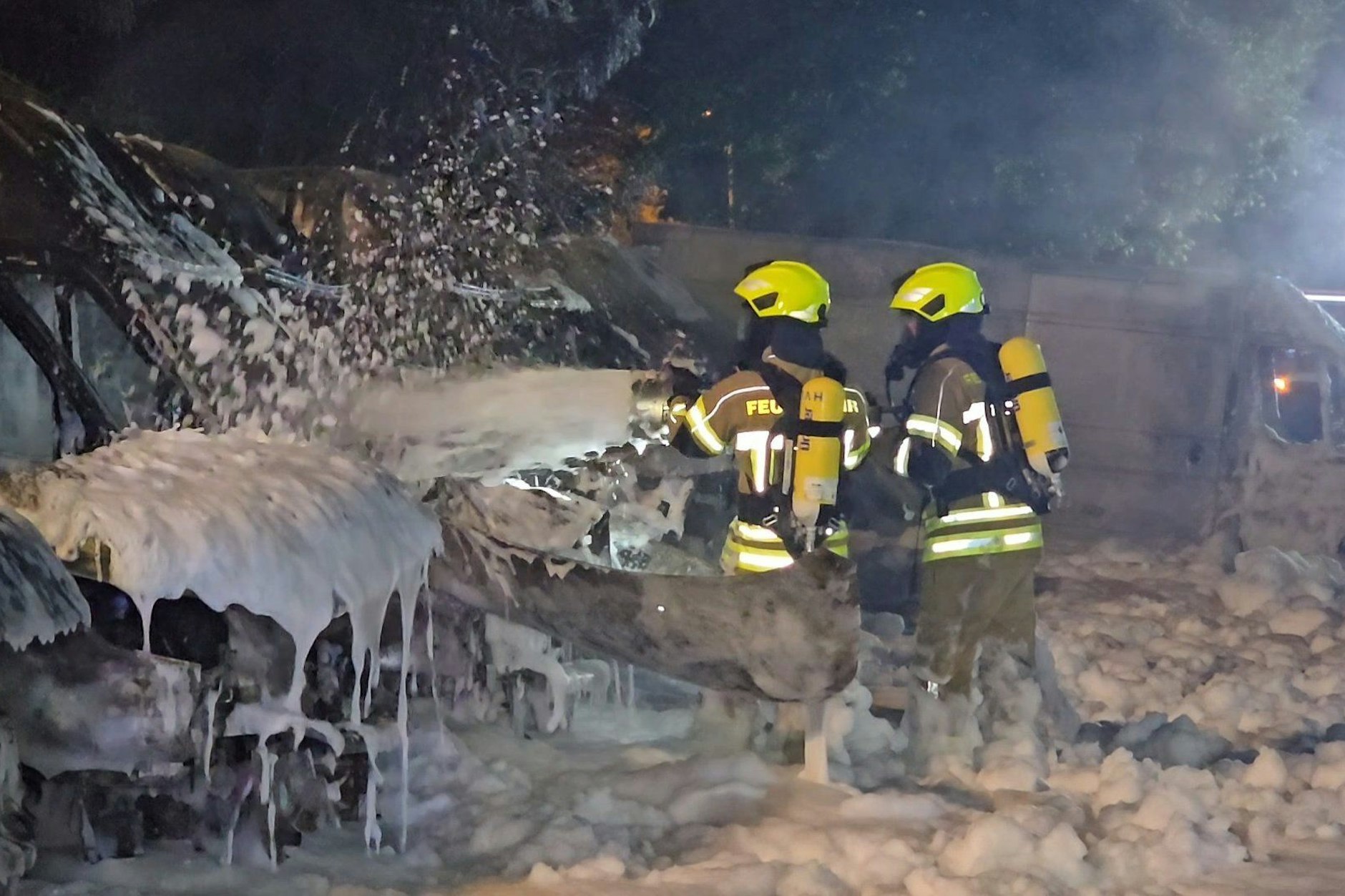 Einsatzkräfte der Feuerwehr löschen Brände an Transportern. Mehr als 20 Transporter fangen nahe Berlin Feuer. Der Brand bleibt lange unbemerkt und richtet großen Schaden an. Die Hintergründe sind noch weitestgehend unklar. 