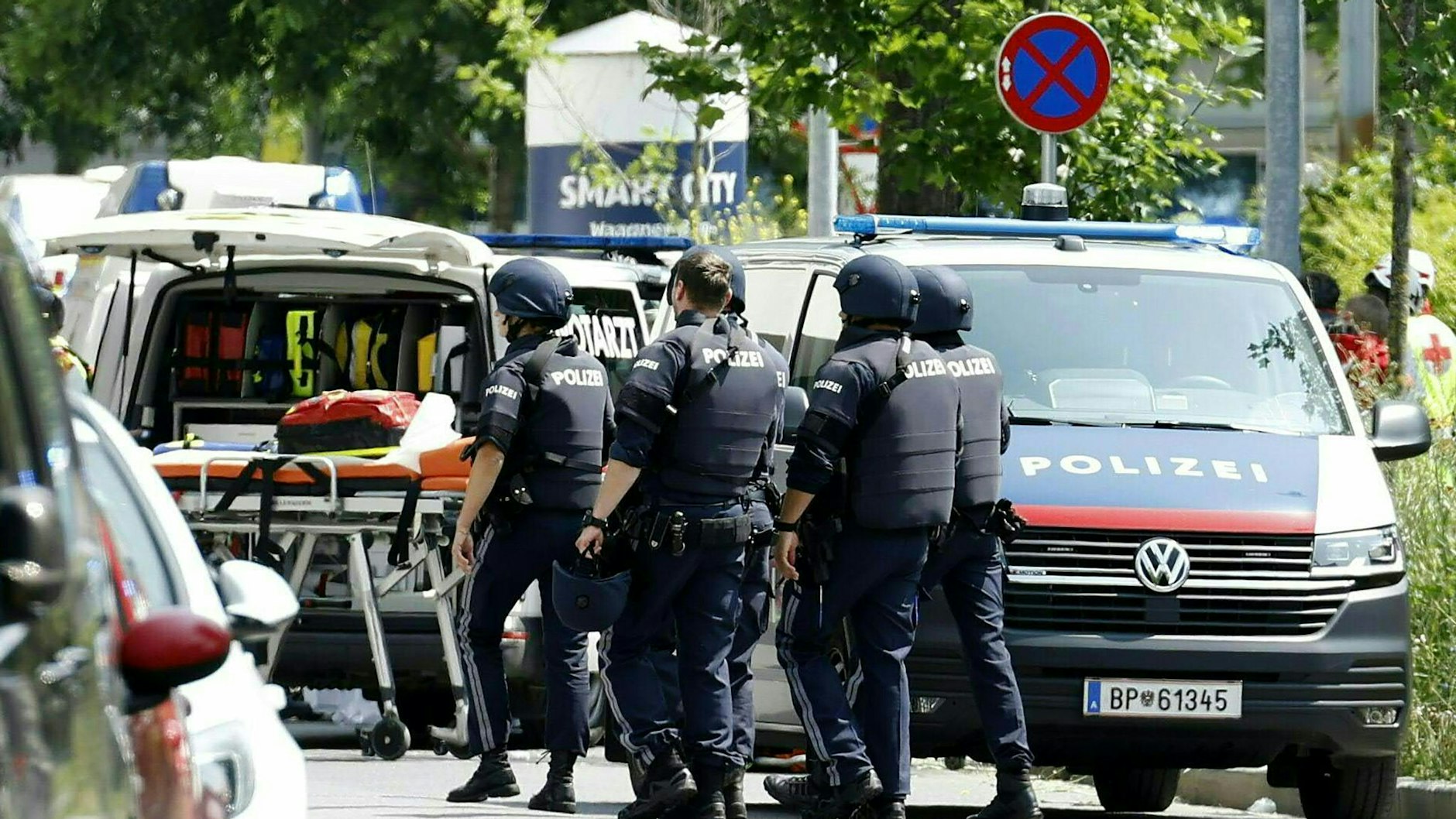 Einsatzkräfte der Polizei stehen in der Nähe des Tatorts an einer Grazer Schule. 