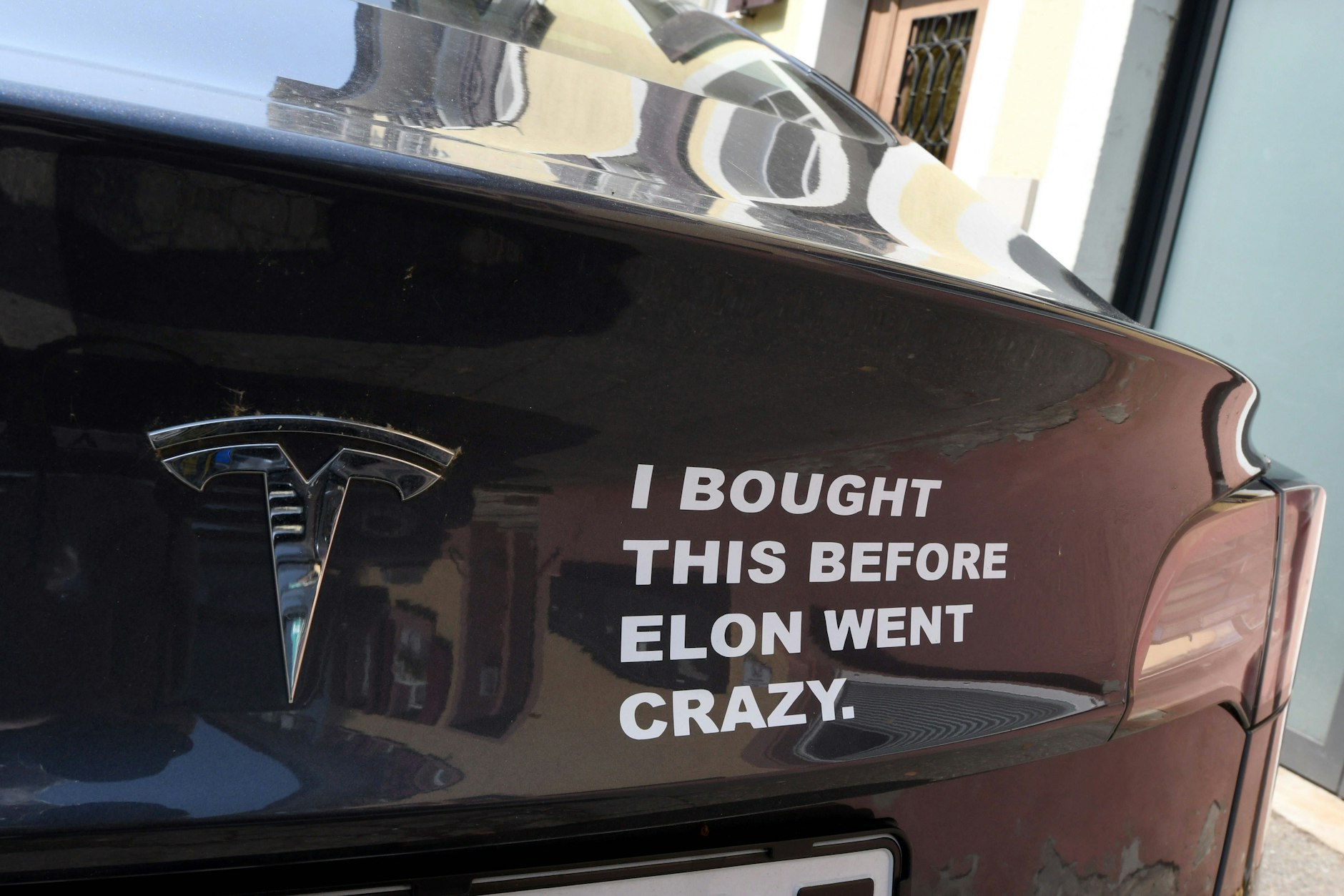 „Ich habe das gekauft, bevor Elon verrückt wurde“ – Aufschrift am Heck eines parkenden Tesla in Freiburg.