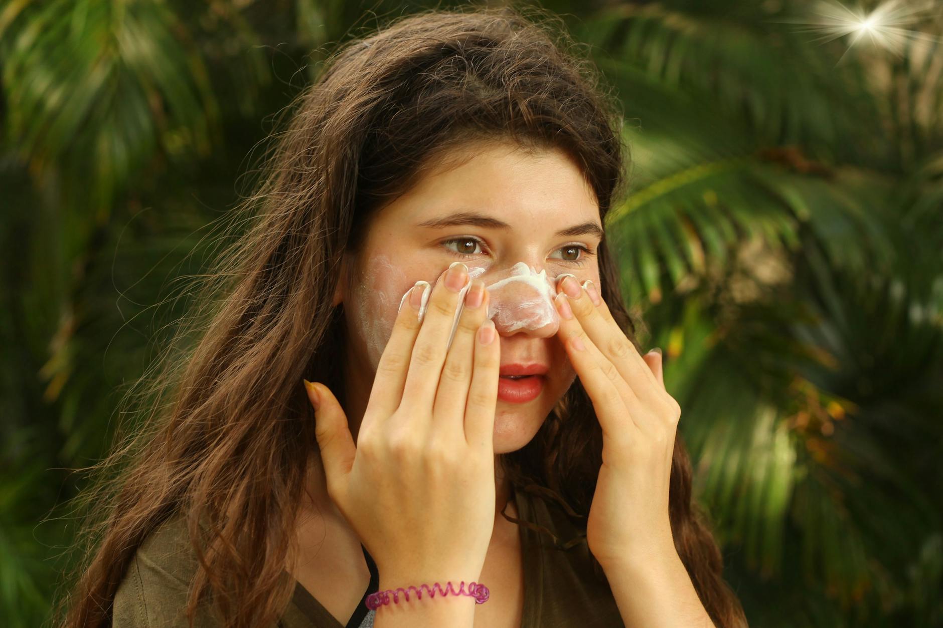 Frau cremt sich das Gesicht ein: Auch Kleidung kann vor gefährlicher Sonnenstahlung schützen.
