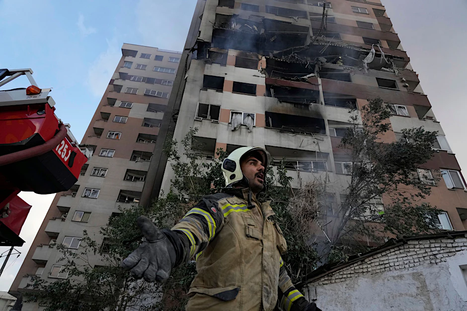 Ein Feuerwehrmann ist in einer Wohnanlage in Teheran im Einsatz, in der es durch israelische Angriffe zu einer Explosion gekommen ist.