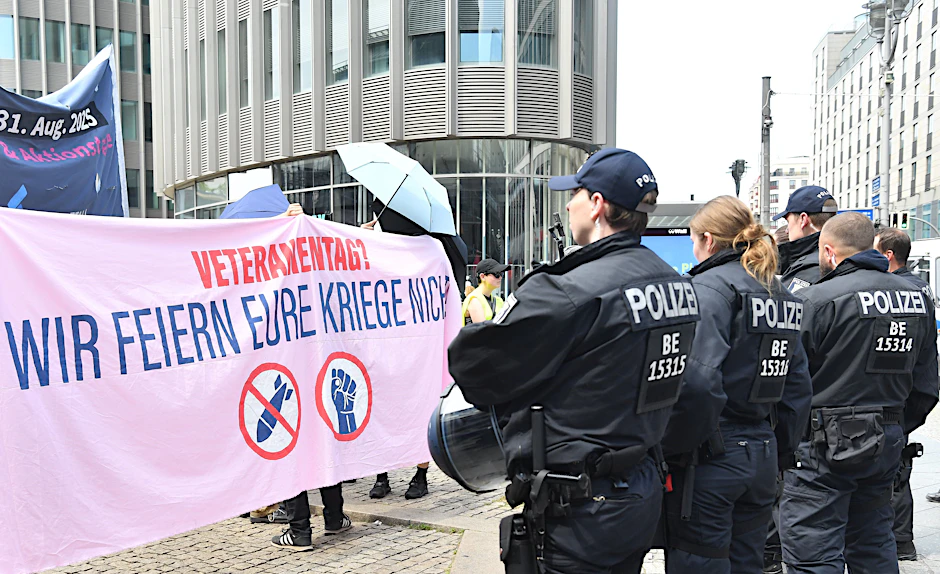 Am ersten Nationalen Veteranentag protestieren am Bahnhof Friedrichstraße Menschen gegen die bundesweit stattfindende Veranstaltung.