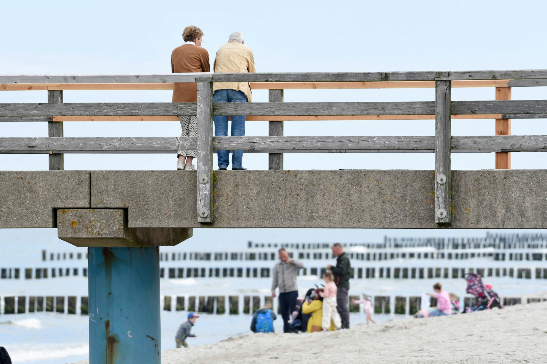 Spaziergänger stehen auf der Seebrücke am gut besuchtem Ostseestrand von Graal-Müritz. Für Rentner ist er ein beliebtes Urlaubsziel.