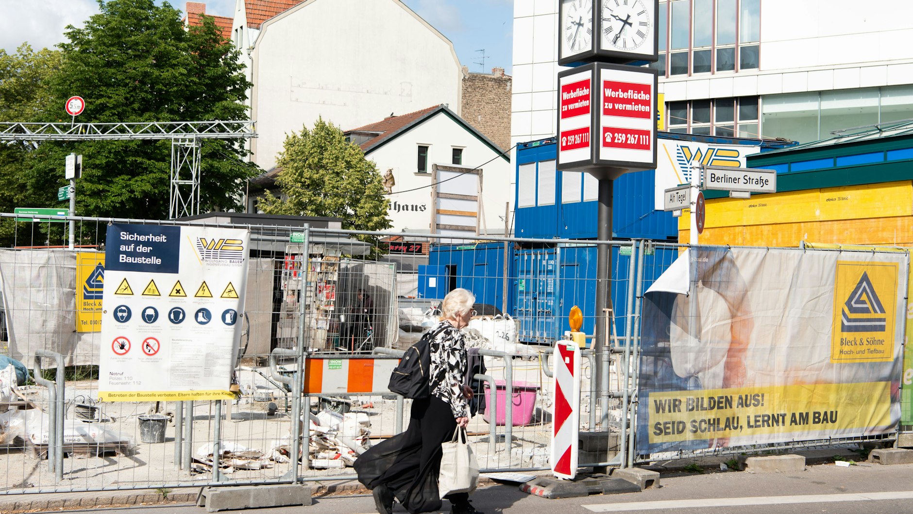 Hinter den Bauzäunen ist der Kiosk kaum wahrnehmbar. Kunden laufen auf der Straße an dem Büdchen vorbei.