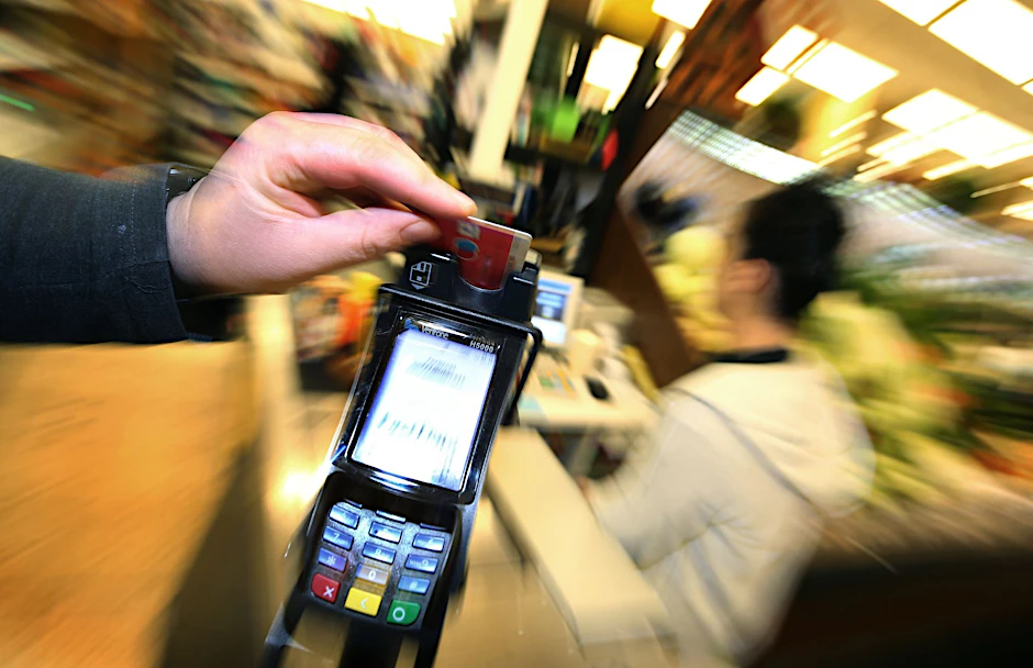 Eine Bezahlkarte wird in den Bezahlterminal an der Kasse eines Supermarktes geschoben.