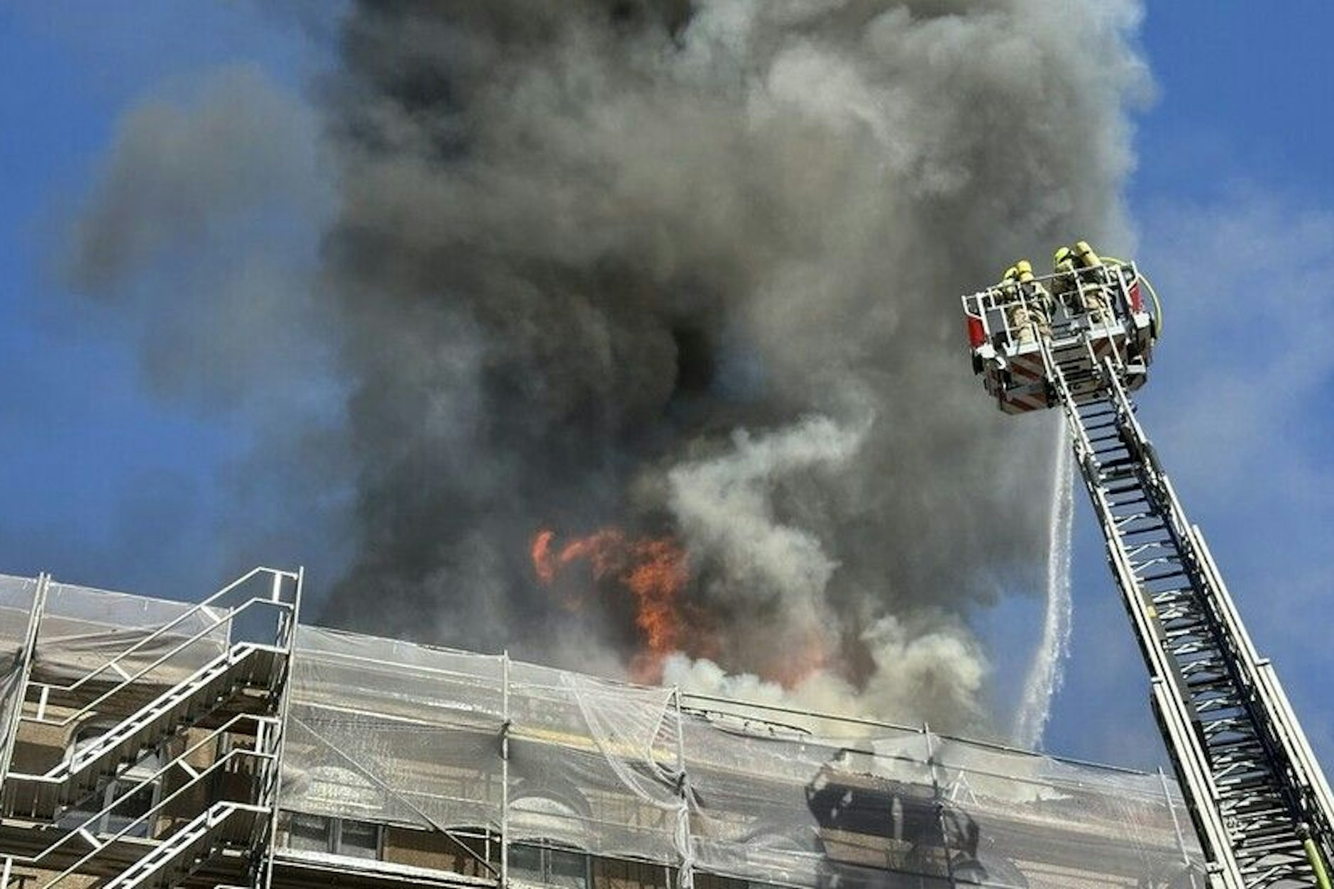 Die Flammen schlagen hoch aus dem Dachgeschoss. Die Feuerwehrleute bekämpfen über eine Drehleiter den Brand.