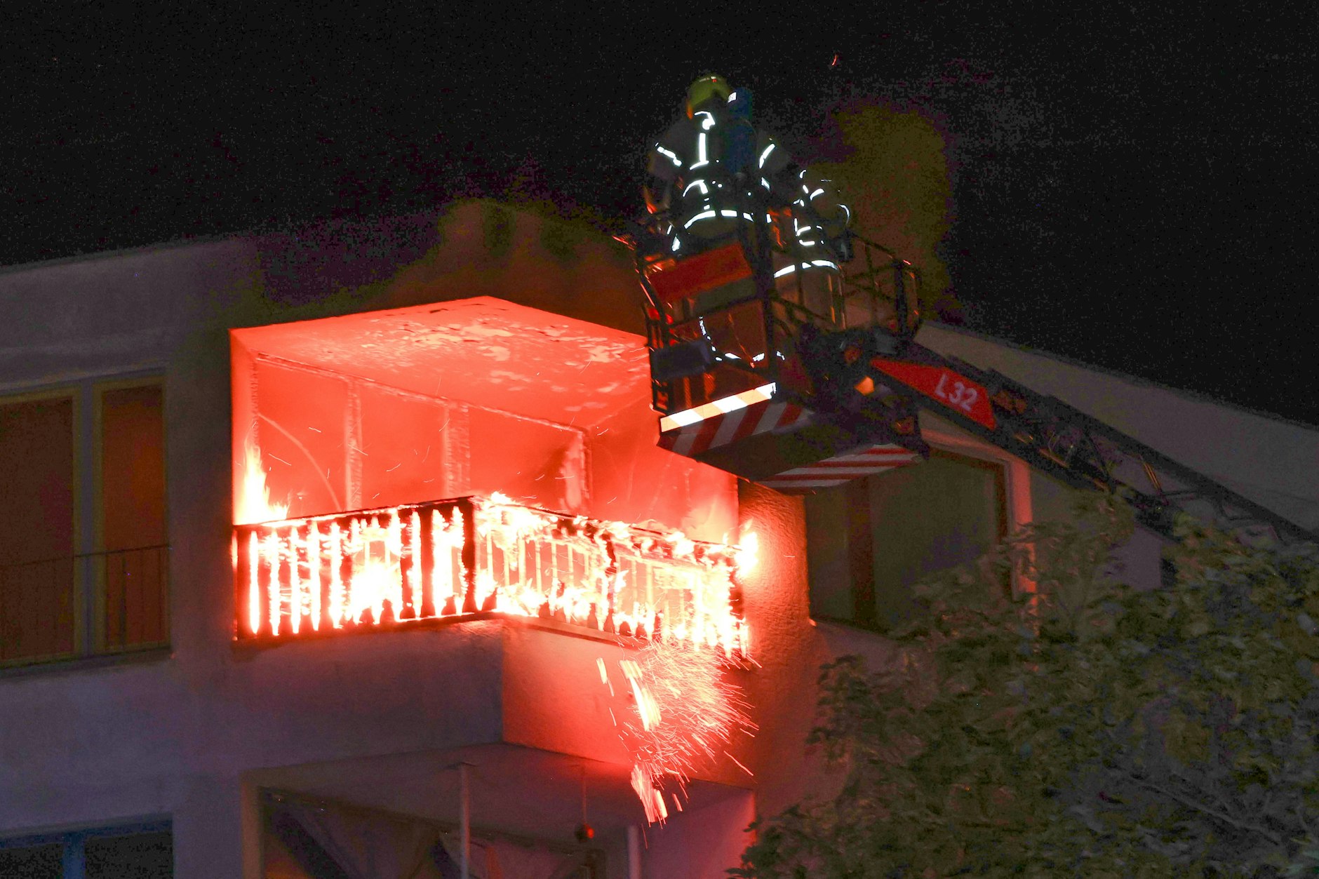 Feuerwehr-Leute auf einber Hebebühne versuchen an der Neuköllnischen Allee, den lichterloh brennenden Balkon zu löschen.