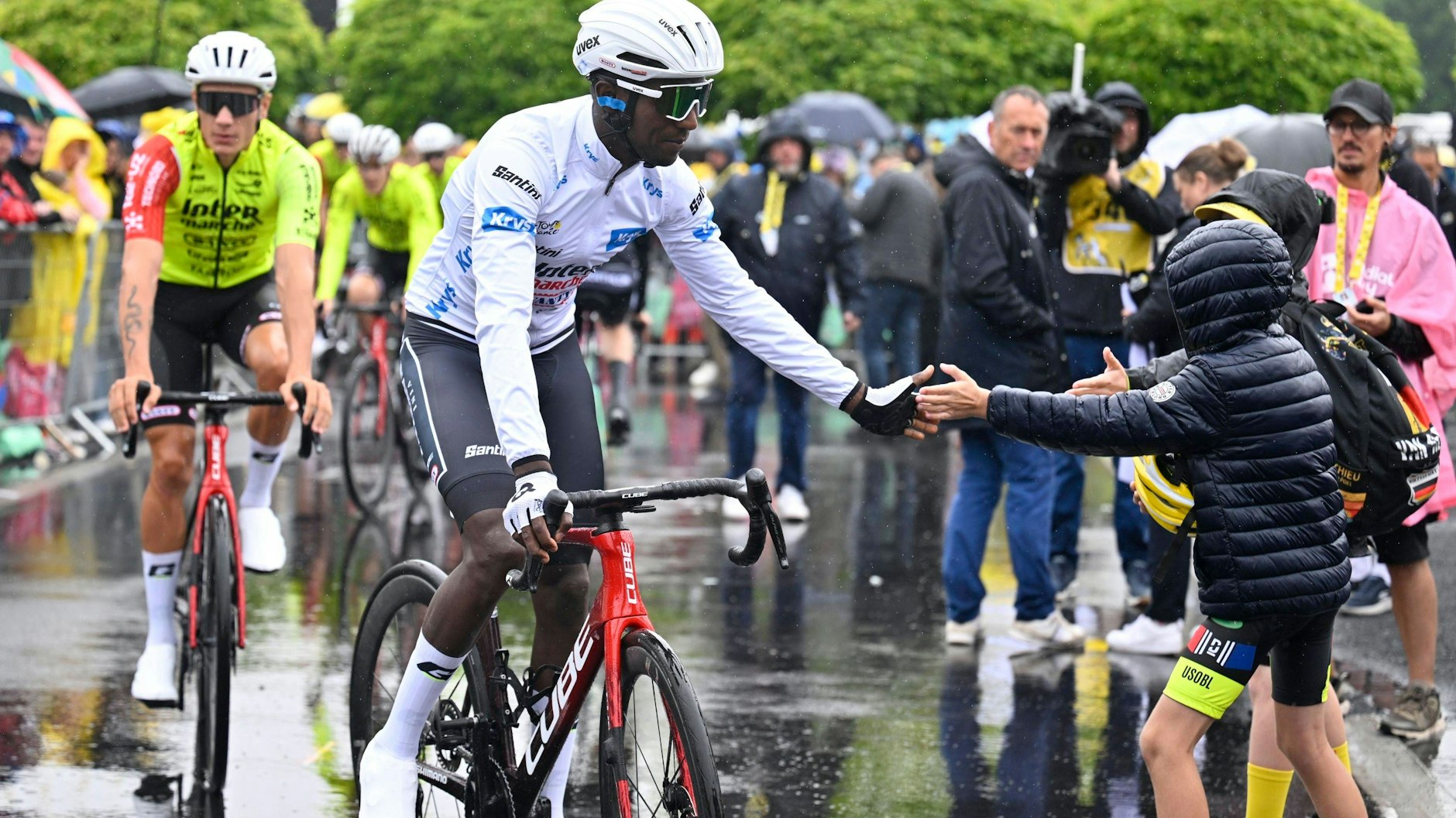 Sprint-Star Girmay Biniam klatscht auf regennasser Straße einen kleinen Radfan ab.