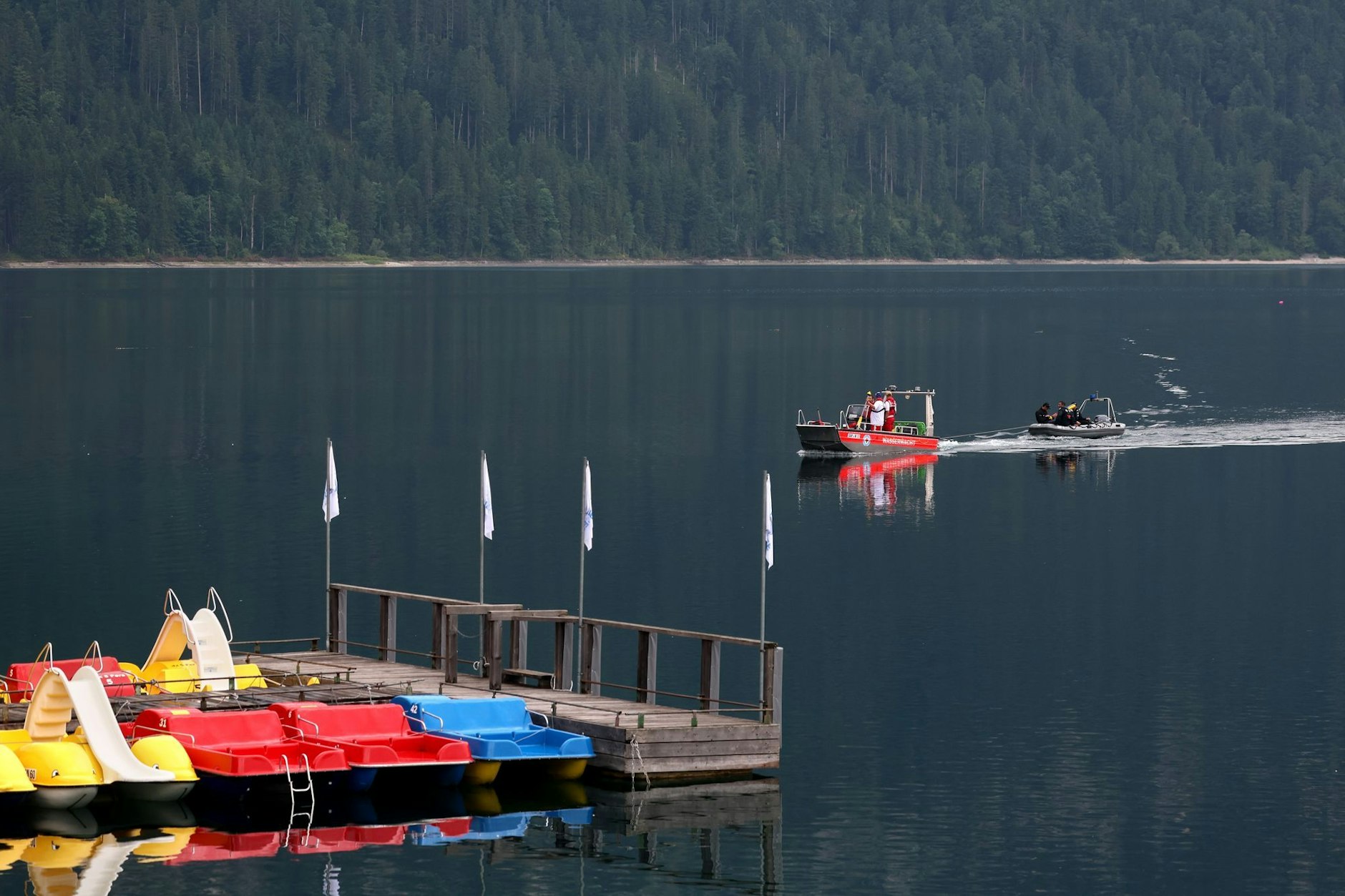 Rettungskräfte von Polizei und Wasserwacht fahren hinter den Tretbooten eines geschlossenen Bootsverleihs über den Eibsee.