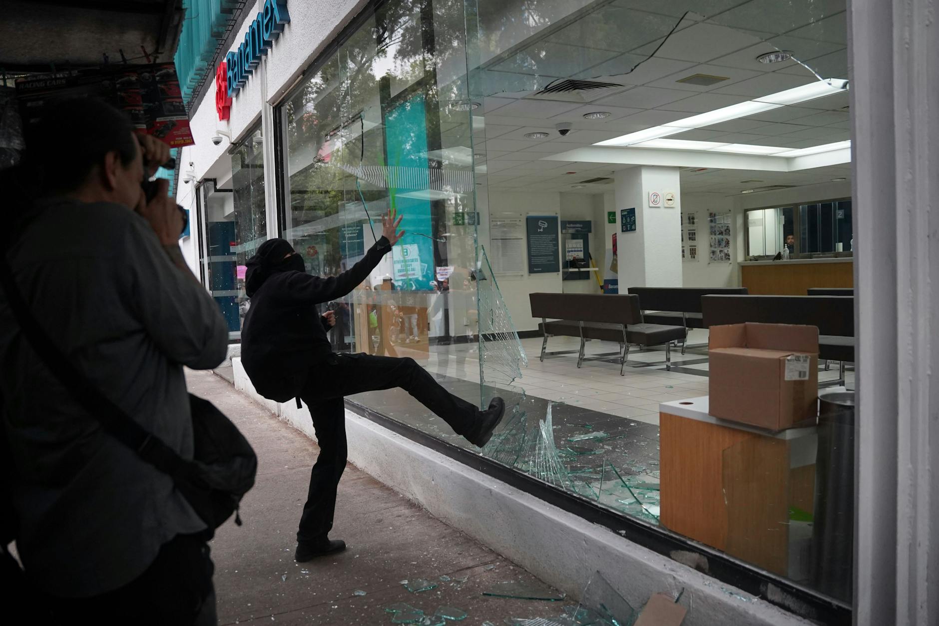 Ein Demonstrant tritt das Schaufenster einer Bank ein, nachdem ein friedlicher Protest gegen die Gentrifizierung gewaltsam ausgeartet ist.