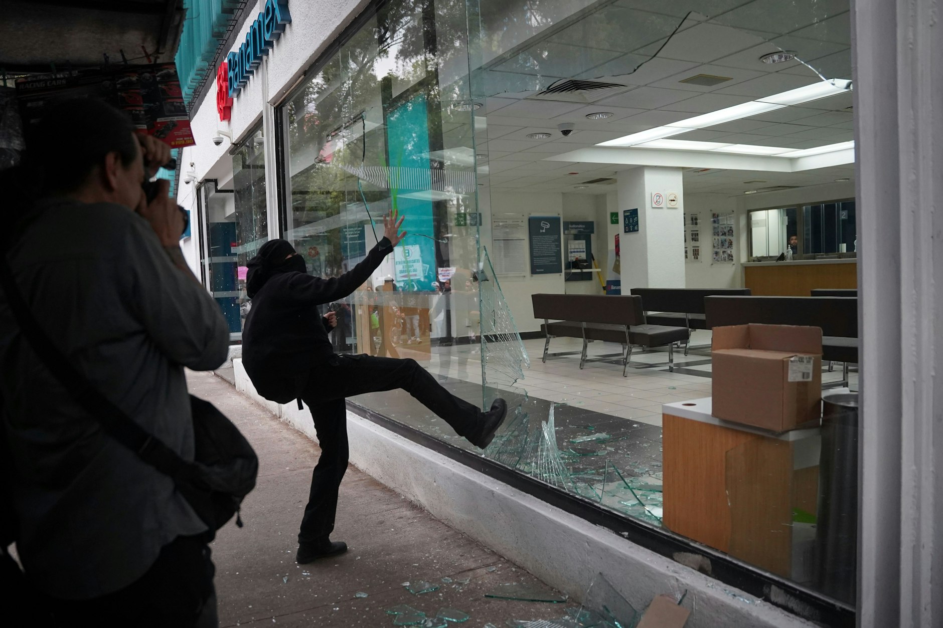 Ein Demonstrant tritt das Schaufenster einer Bank ein, nachdem ein friedlicher Protest gegen die Gentrifizierung gewaltsam ausgeartet ist. 