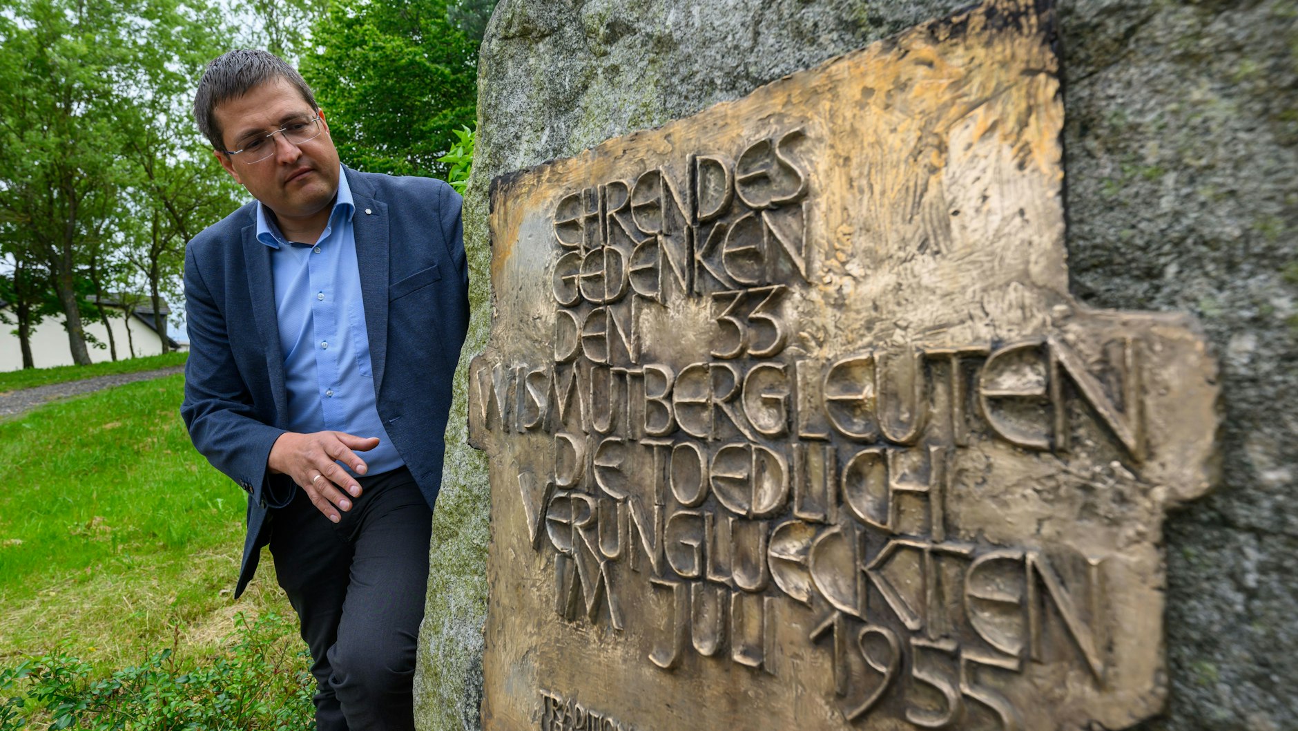 Andy Tauber, Bereichsleiter der Wismut GmbH, steht neben einer Gedenktafel mit der Aufschrift „Ehrendes Gedenken den 33 Wismutbergleuten die tödlich verunglückten im Juli 1955“ am Ehrenhain in Bad Schlema. Die Gedenkstätte wurde 1996 am früheren Schacht 250 eingerichtet.