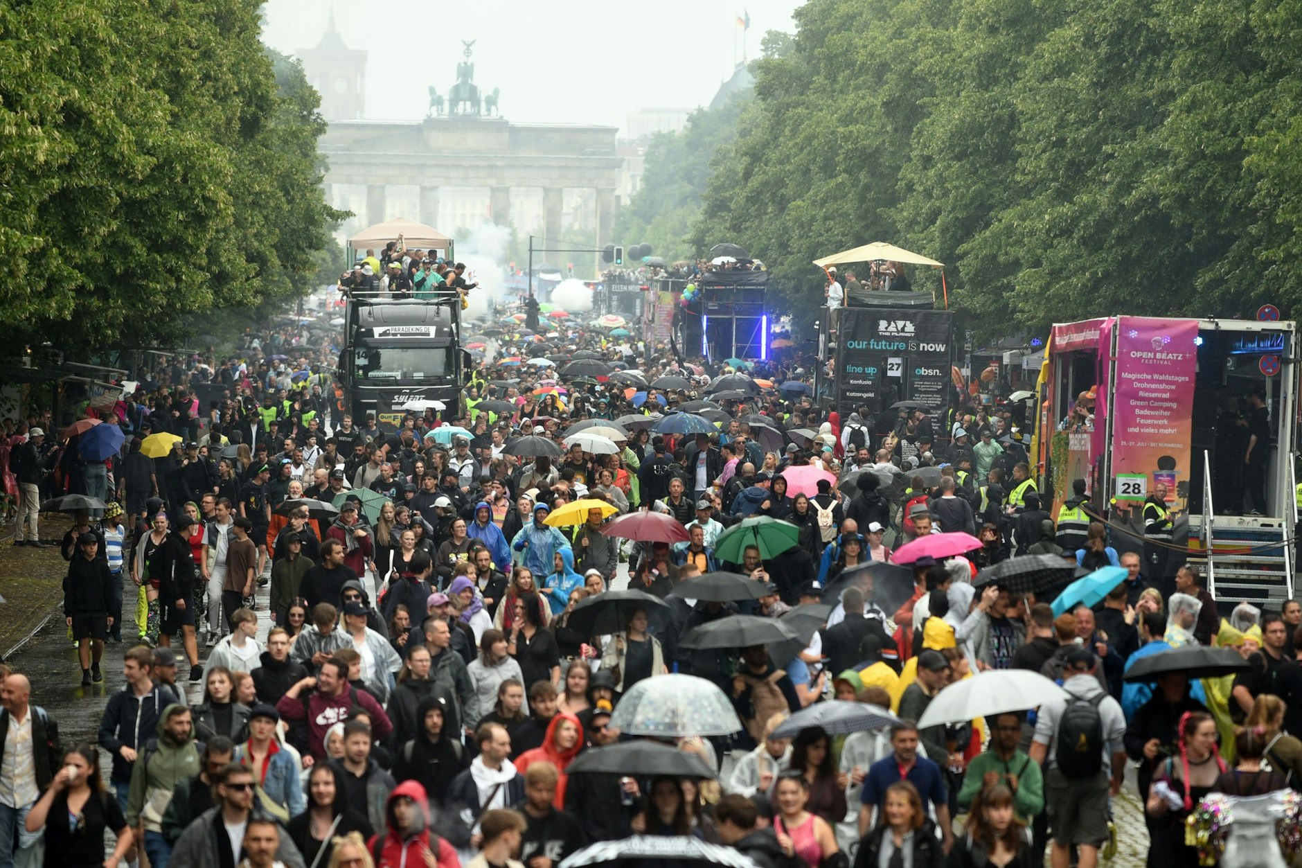 Blick von oben auf die bunten Wagen und tanzenden Menschen bei der „Rave the Planet“-Parade am Berliner Tiergarten.