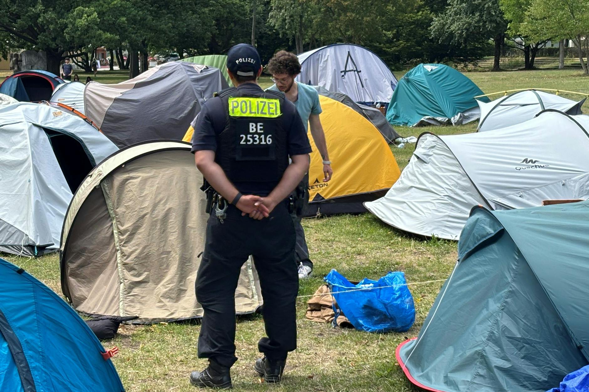 Ein Polizist passt auf, wie ein Bewohner des Protestcamps seine Sachen zusammenräumt.