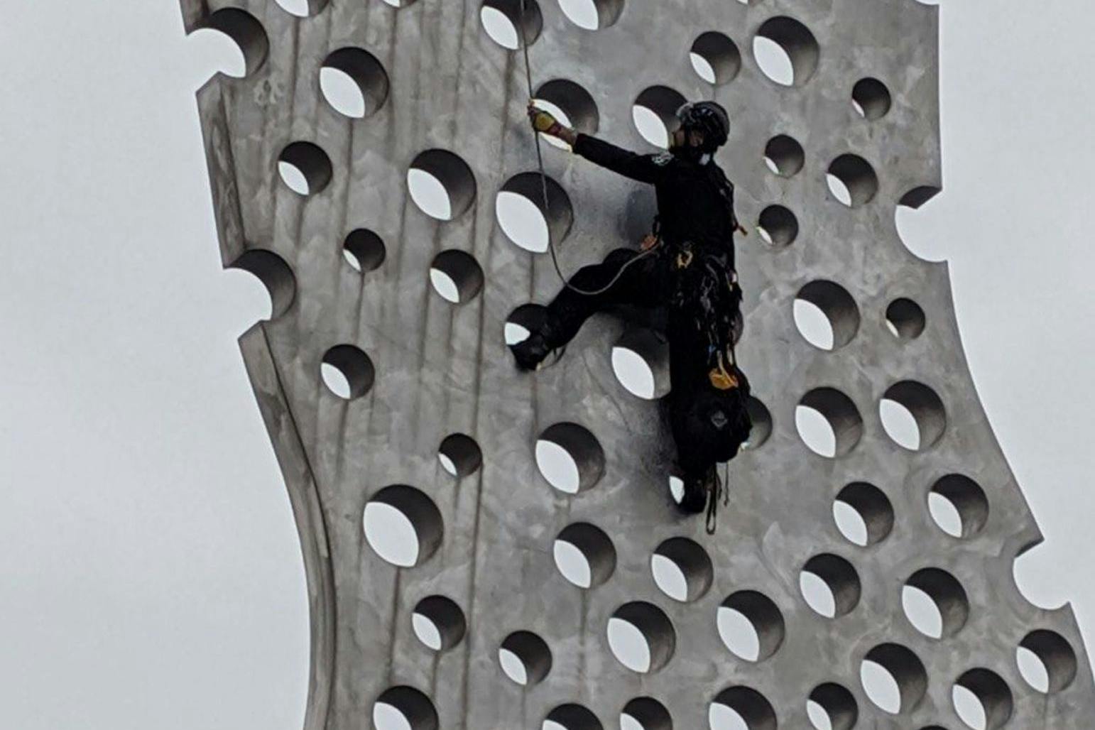 Einsatz am berühmten „Molecule Men“: Polizisten mussten auf die Skulptur klettern, um das Transparent wieder zu entfernen.
