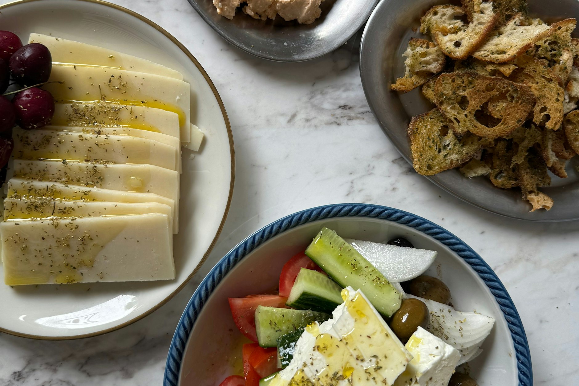 Oben Tyrokafteri, ein pikanter Fetakäsedip, links Graviera Hartkäse aus dem Epirusgebirge, rechts Brotchips aus der Keit-Bäckerei sowie griechischer Bauernsalat mit Fetakäse