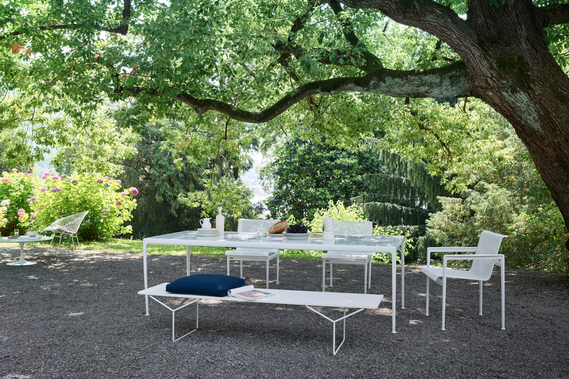 Arkadisch: Esstisch und Stühle aus der Kollektion „1966“ von Knoll International, ges. bei Modus. Dazu gesellt sich die Outdoor-Version der berühmten Bertoia-Bank von 1952, ebenfalls Knoll. Die Holzlatten des Originals wurden dafür durch solche aus Acrylstein ersetzt. Der hält allem stand.